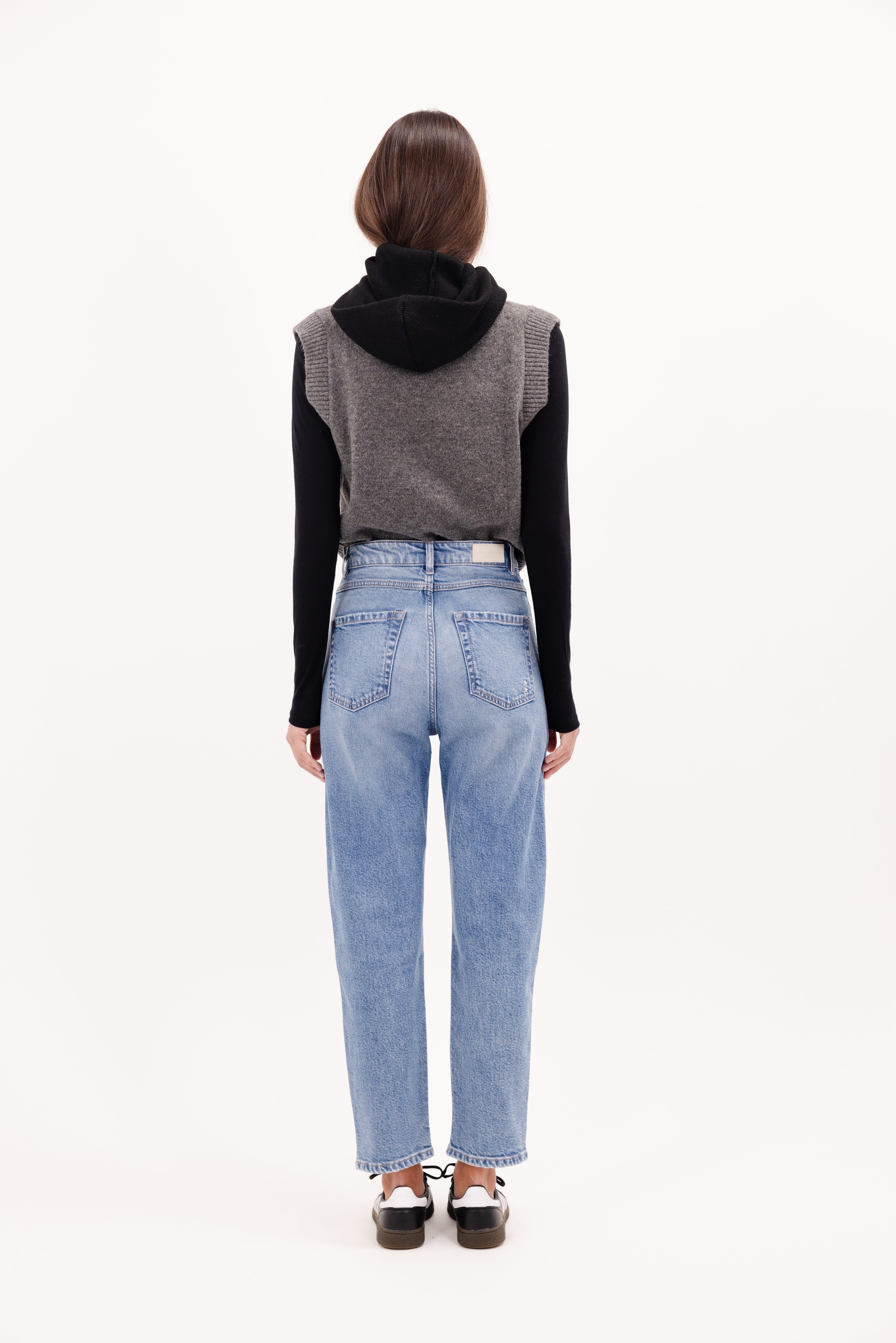 Back view of Karolina women’s carrot jeans in misty blue wash, 99% cotton denim and 1% Elastan fibers, worn by a model with a gray knit.