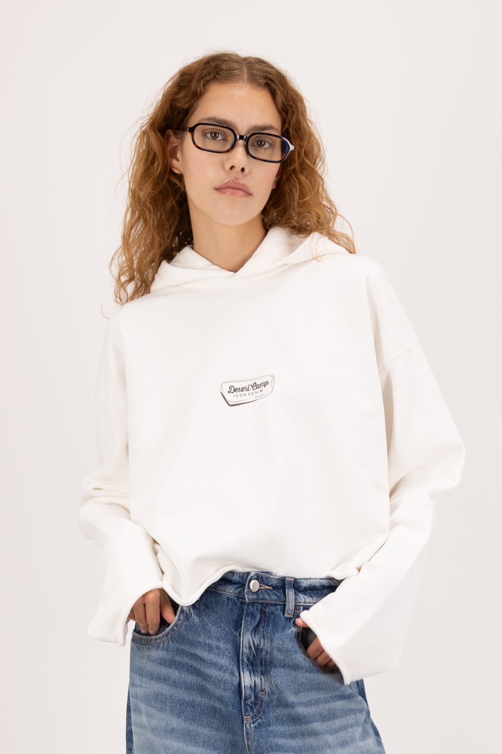 Kay women’s cropped hoodie in white, 100% cotton, worn by a model with jeans.