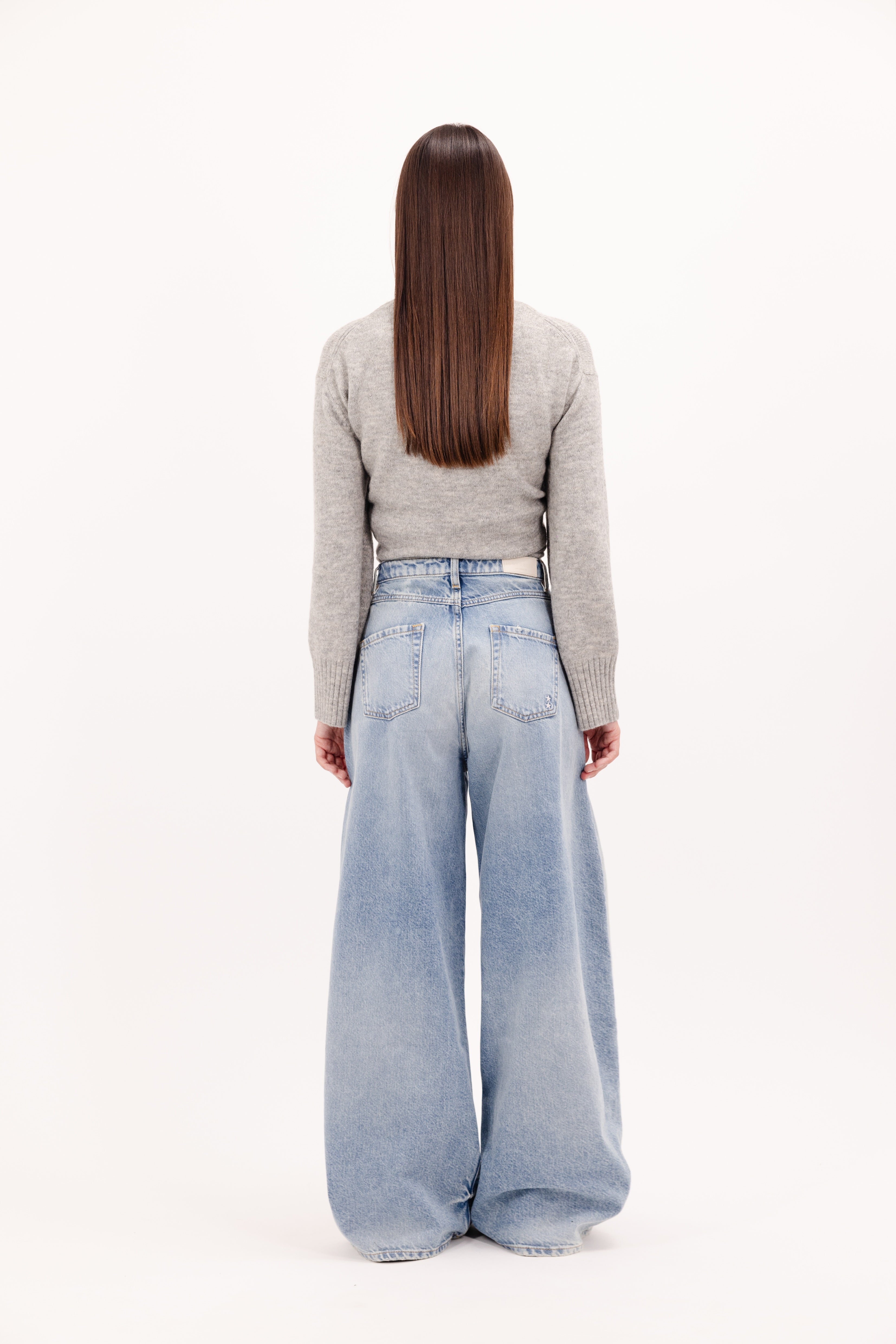 Back view of Kendall women’s wide leg jeans in smoke blue wash, 100% rigid cotton denim, worn by a model with a grey knit.
