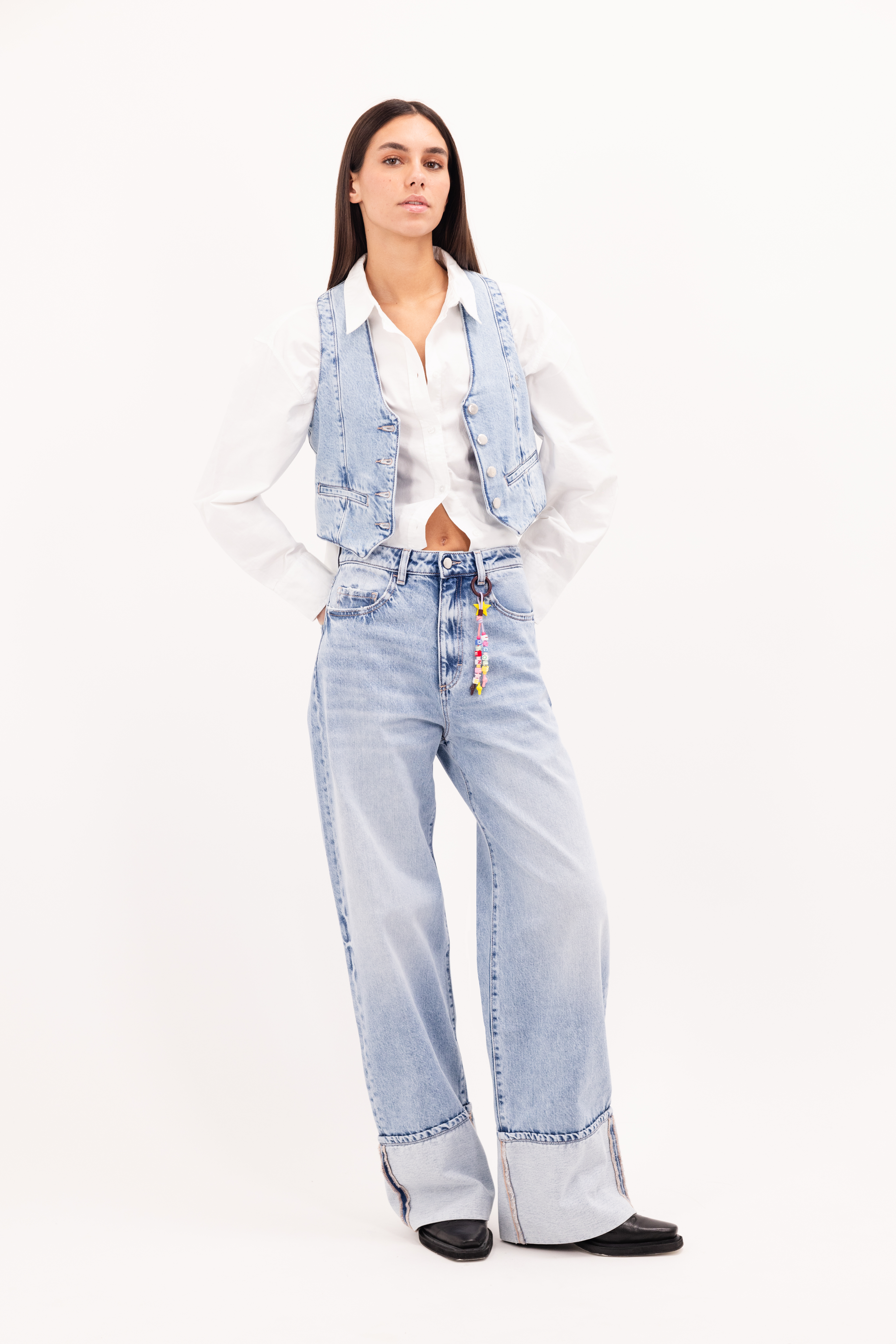 Kiki women’s wide leg jeans in sky blue wash, 100% rigid cotton denim, worn by a model with a shirt and denim vest.
