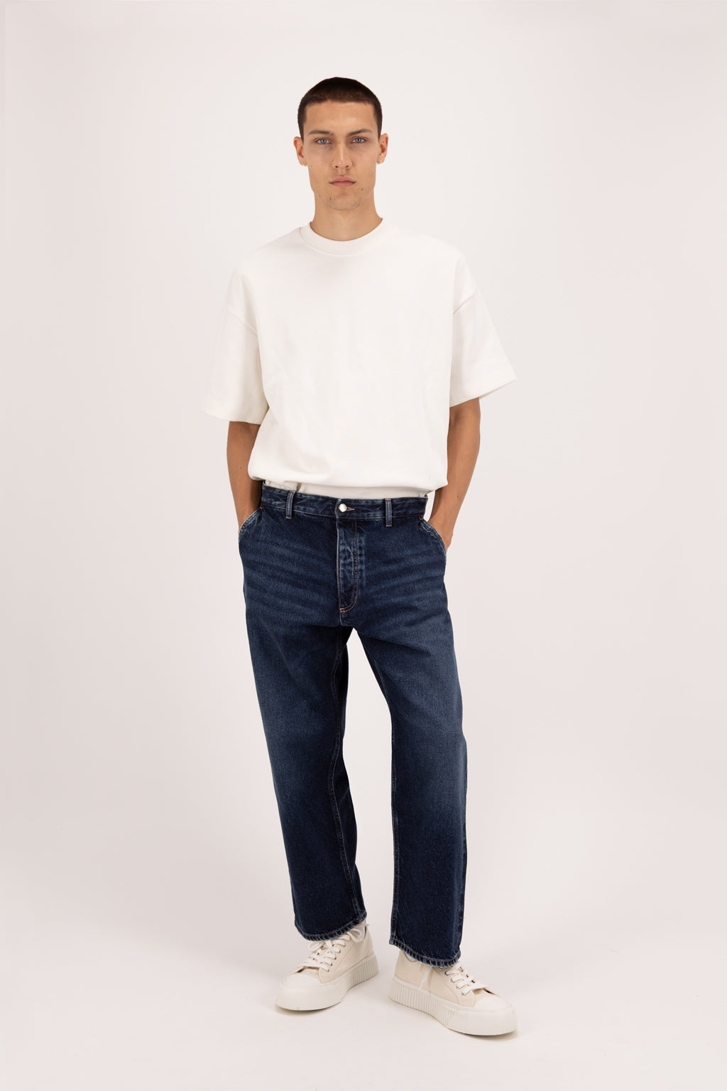 Leo men’s wide curt cropped jeans in deep blue wash, 100% rigid cotton denim, worn by a model with a white t-shirt.