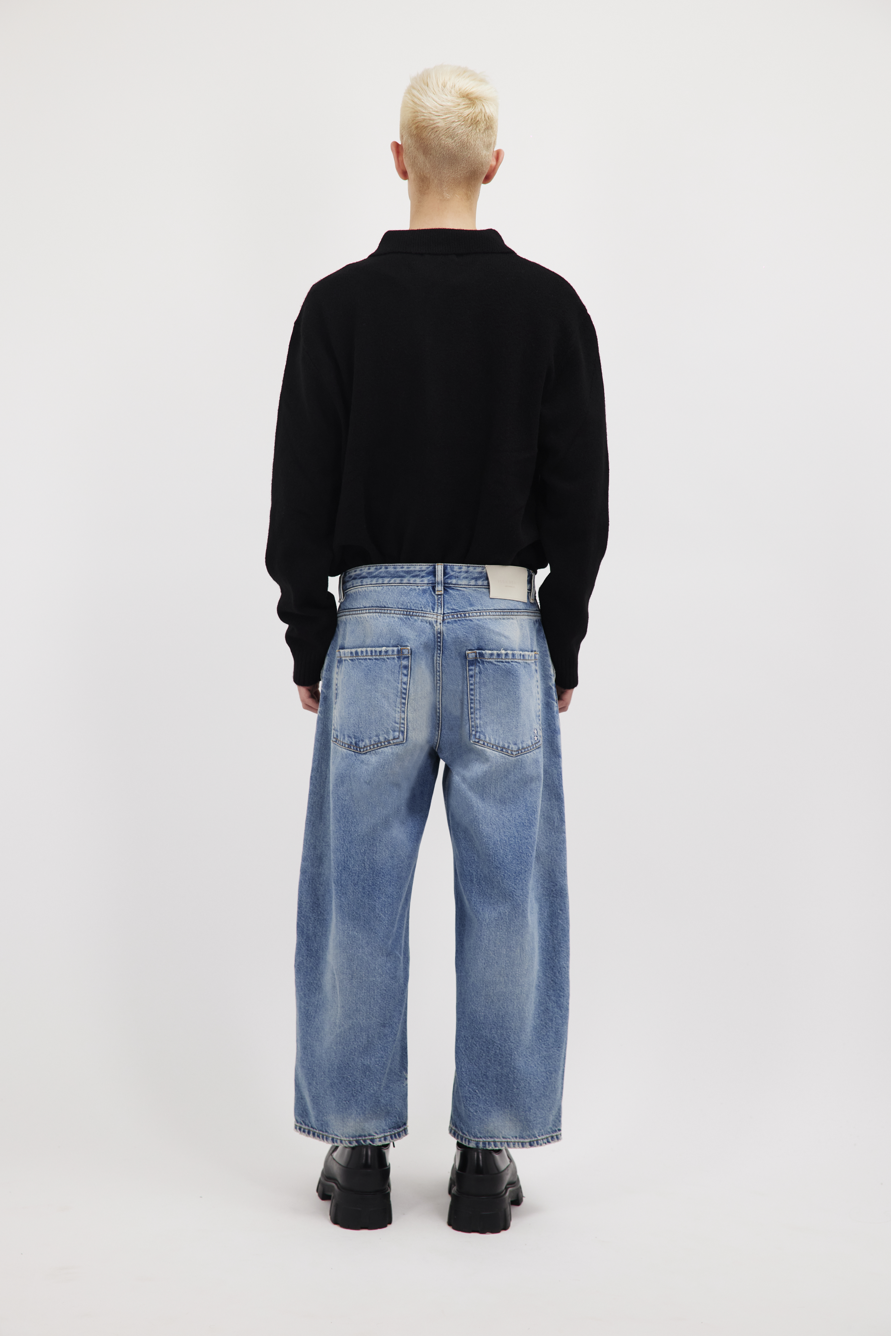 Back view of Leo men’s wide leg crop jeans in smoke blue wash, 100% rigid cotton denim, worn by a model with a black cardigan.