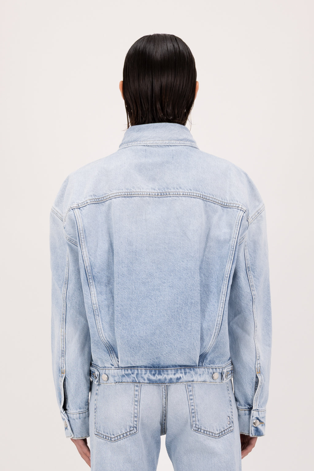 Back view of Lori women’s jacket in sky blue wash, 100% rigid cotton denim, worn by a model with jeans.