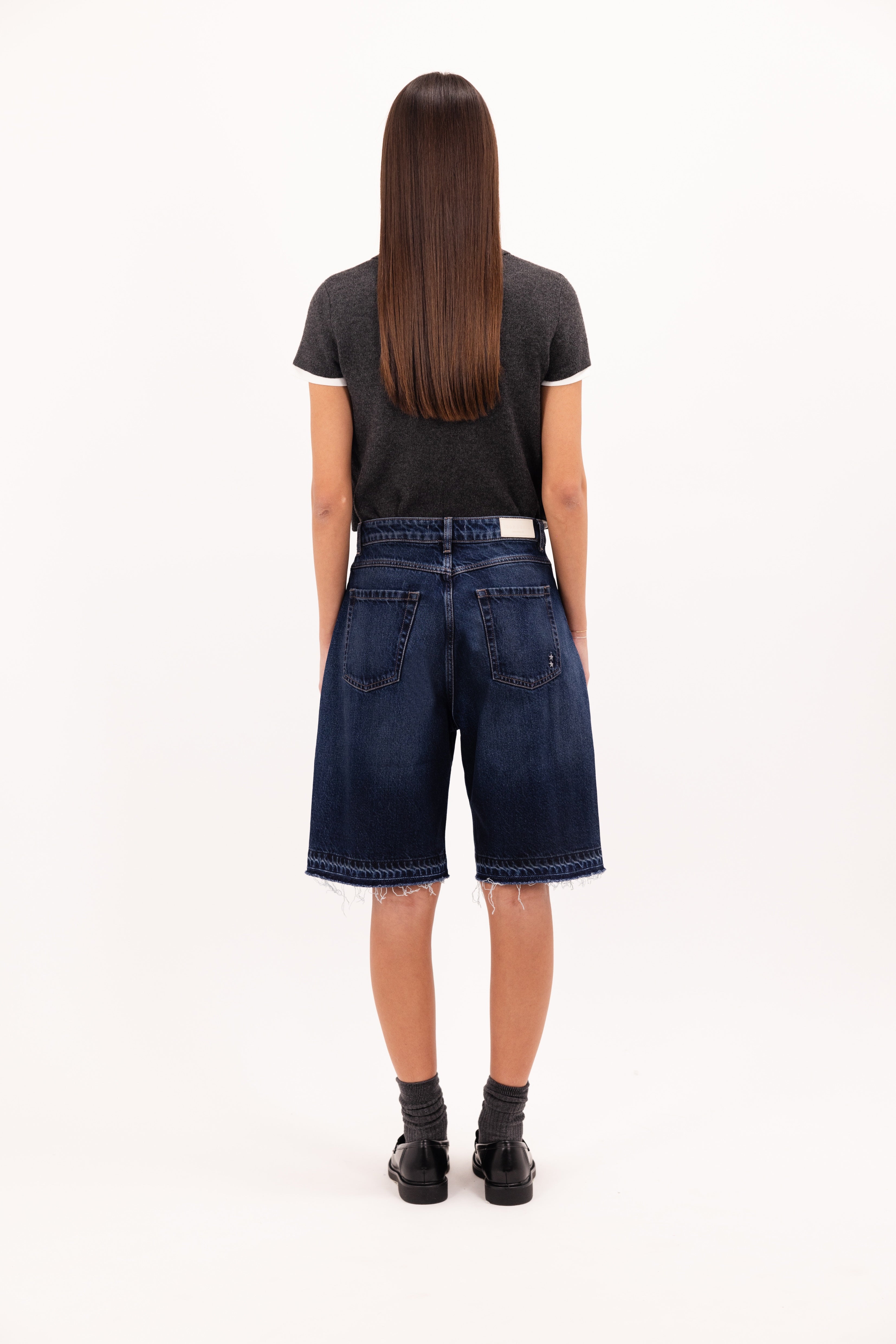 Back view of Lulu women’s wide leg short in dusty blue wash, 100% rigid cotton denim, worn by a model with a wool top.