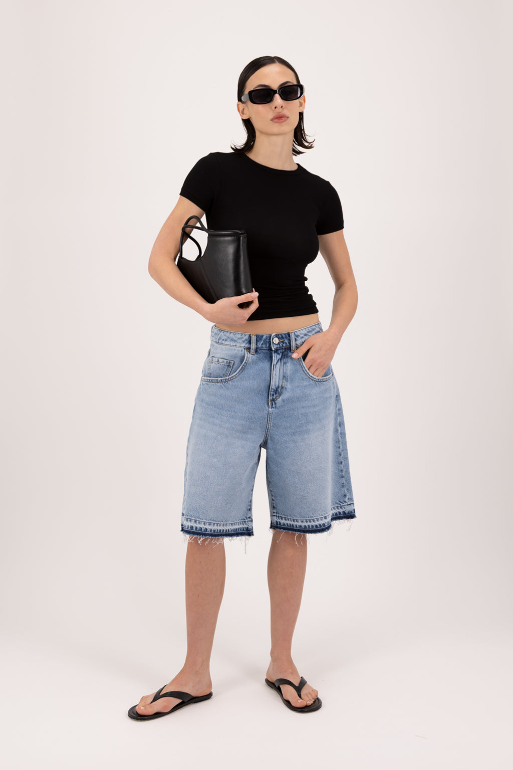 Lulu women’s wide leg short in sky blue wash, 100% rigid cotton denim, worn by a model with a black top.