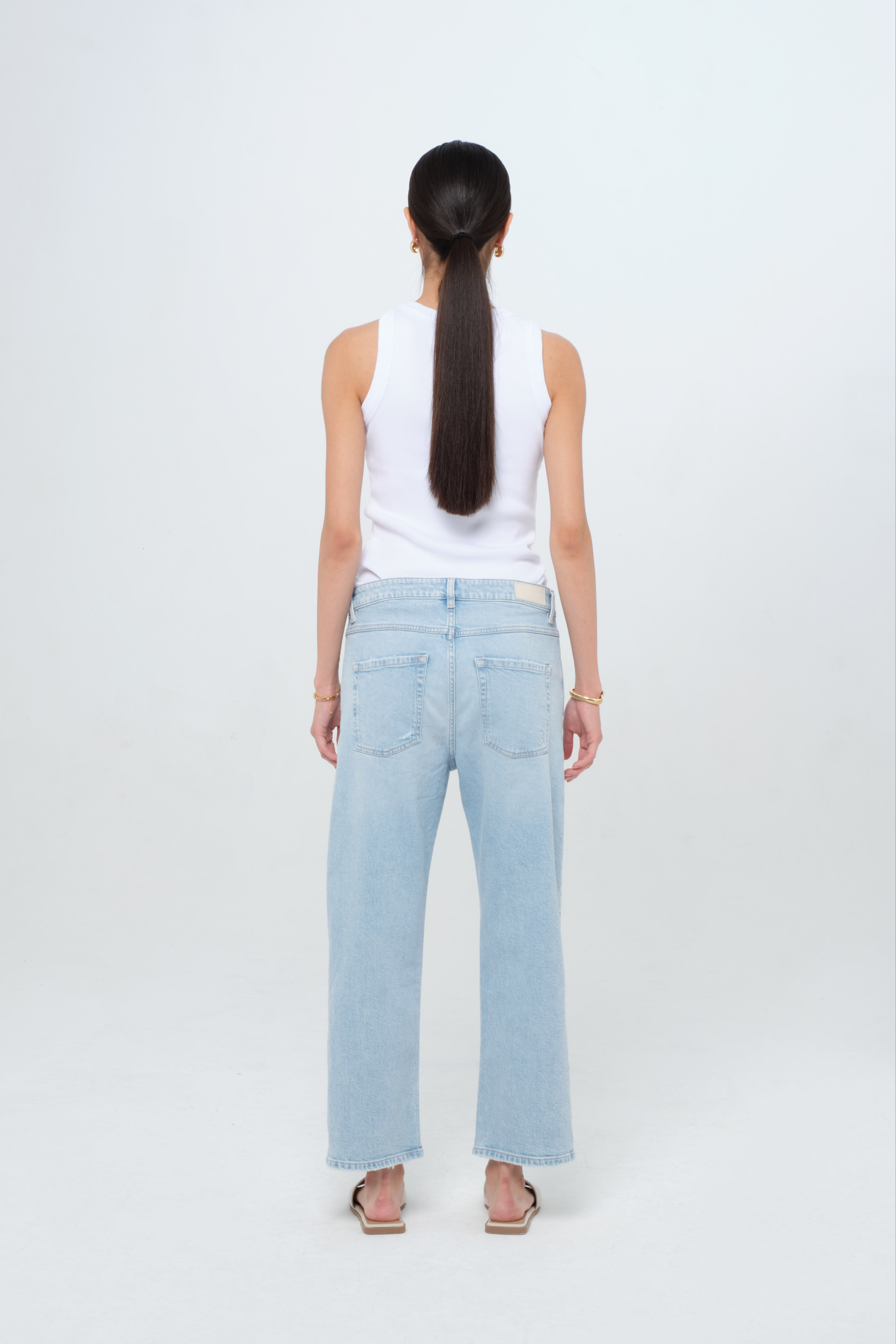 Back view of Mimi women’s straight leg jeans in light wash, 100% cotton denim, worn by a model with a white tank top.