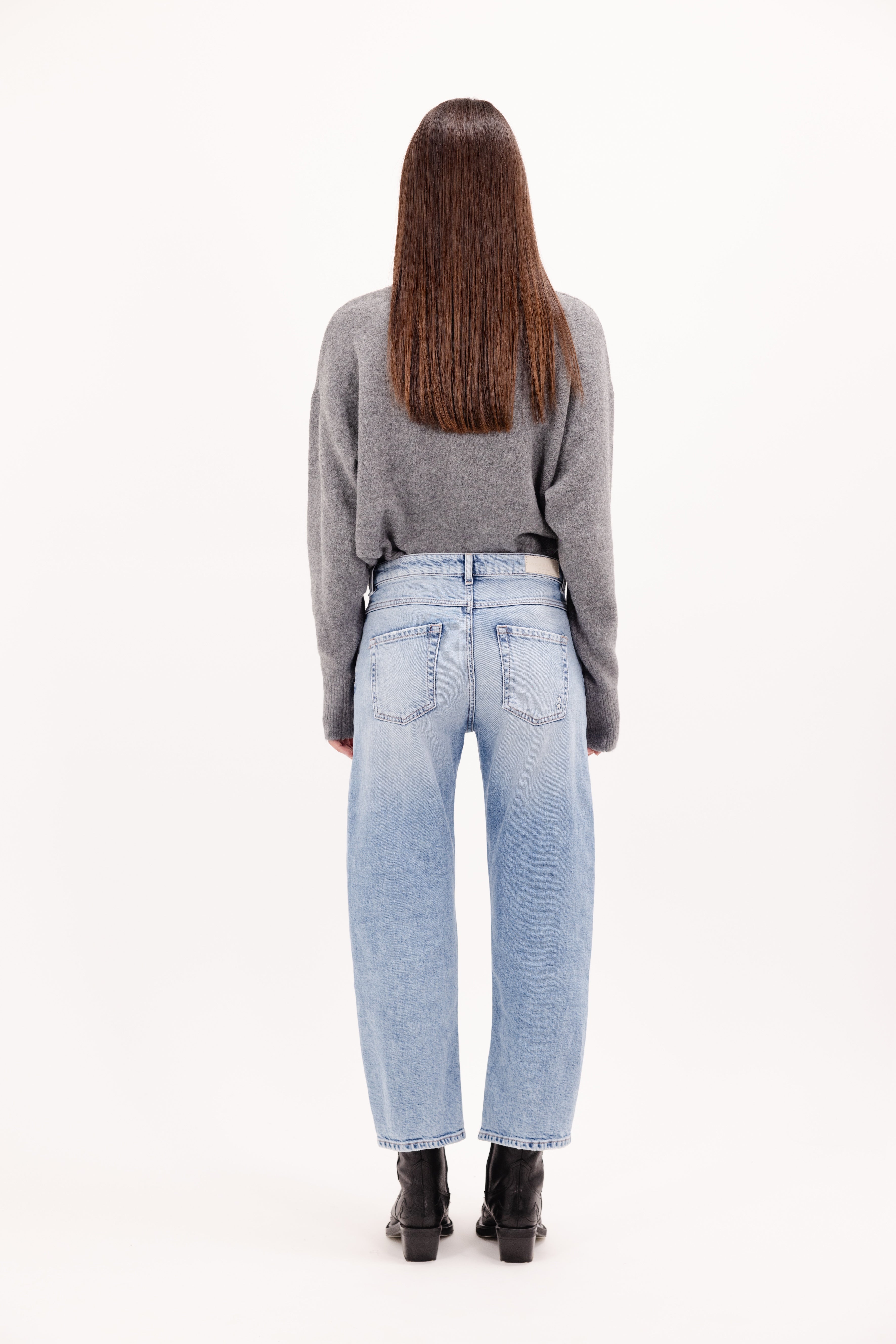 Back view of Mimi women’s straight leg jeans in sky blue wash, 99% cotton denim and 1% Elastan fibers, worn by a model with a gray knit.