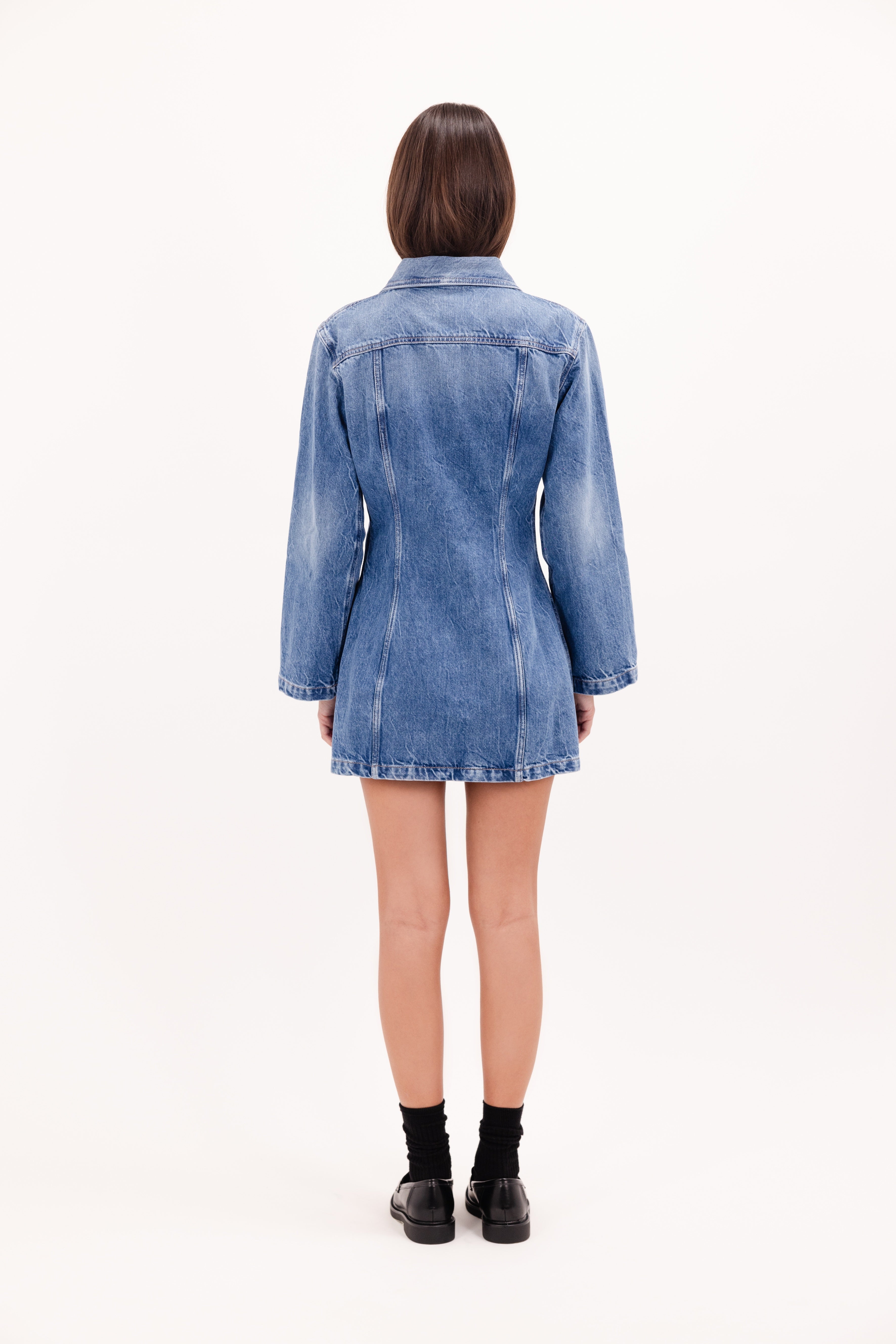 Back view of Mya women’s dress in eclipse wash, 100% rigid cotton denim, worn by a model.