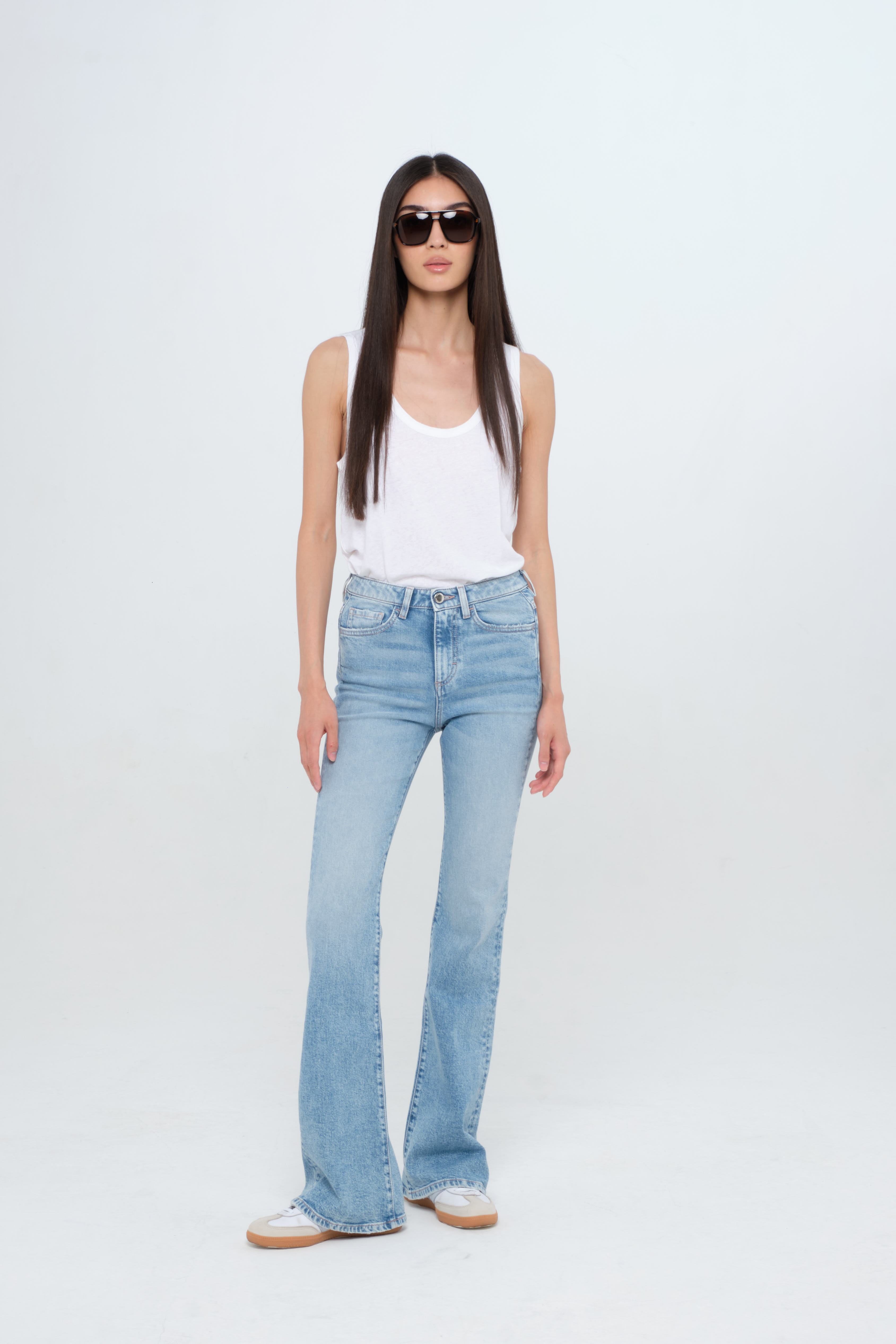 Natie women’s flared leg jeans in light wash, 99% cotton denim and 1% elastan fibers, worn by a model with a white t-shirt.
