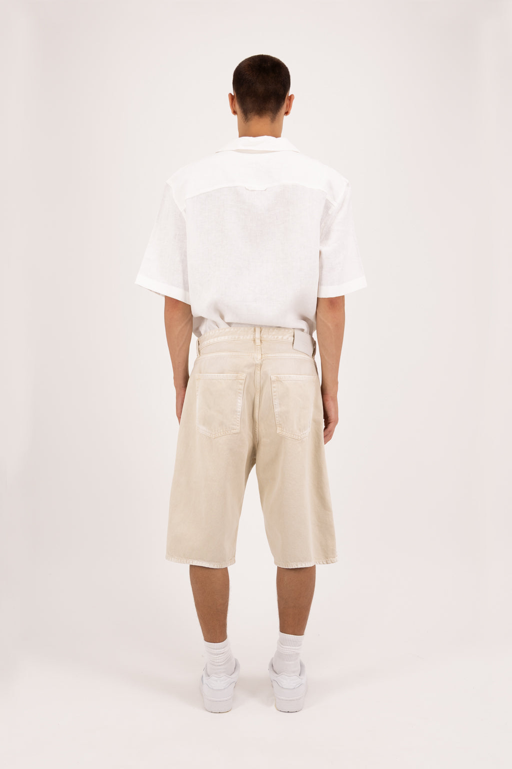 Back view of Bobby men’s wide leg short jeans in desert wash, 100% rigid soft cotton denim, worn by a model with a white shirt.