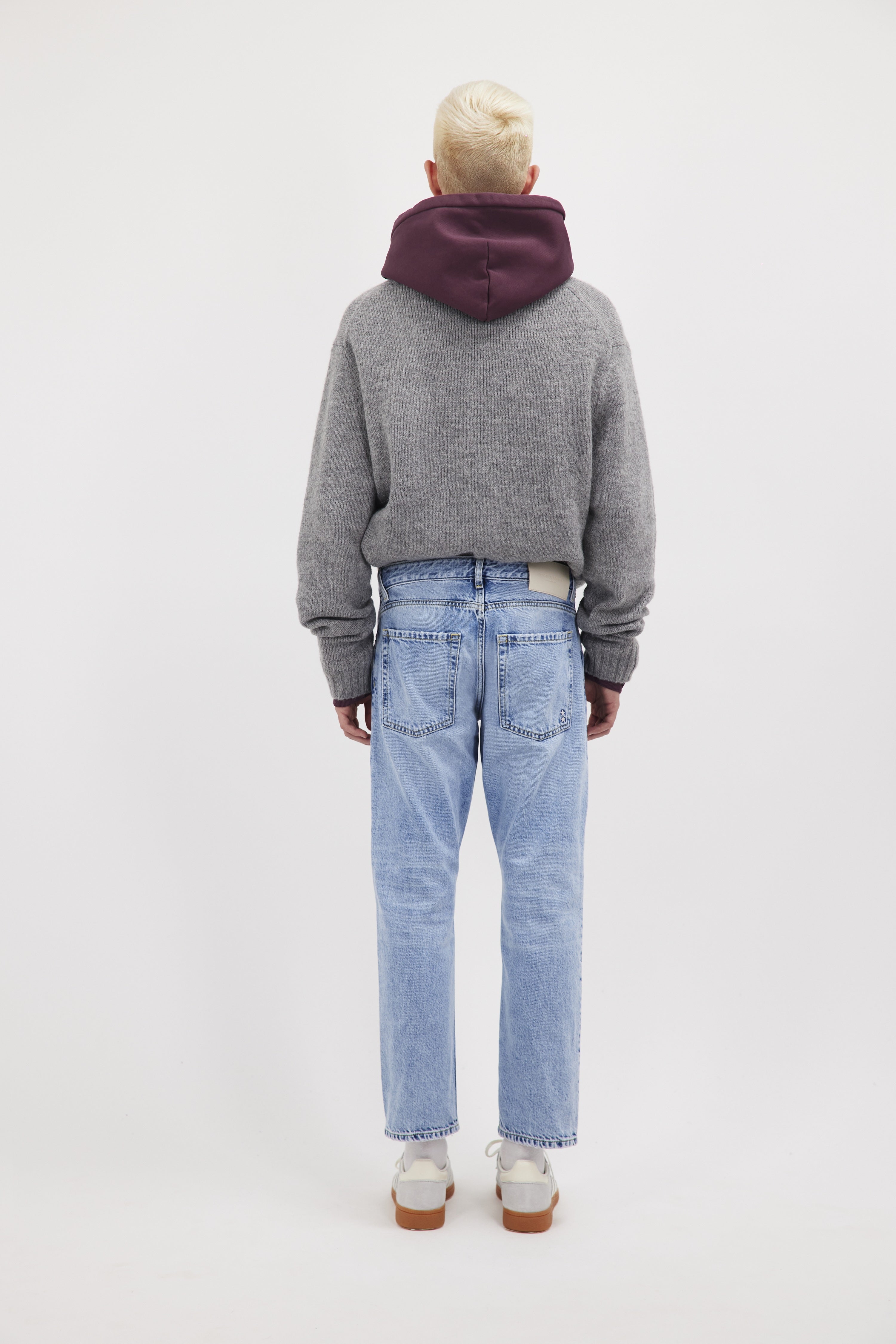 Back view of Nick men’s regular jeans in sky blue wash, 100% rigid cotton denim, worn by a model with a gray knit.