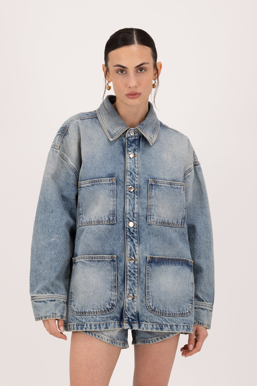 Nika women’s utility jacket in smoke blue wash, 100% rigid cotton denim, worn by a model with shorts.