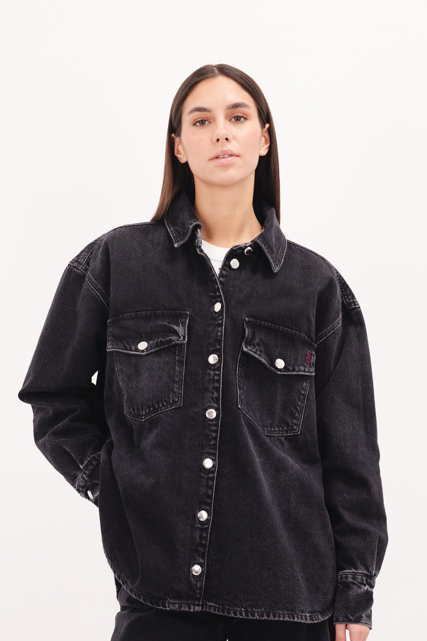 Noa women’s oversize shirt in graphite black wash, 100% rigid cotton denim, worn by a model with jeans.