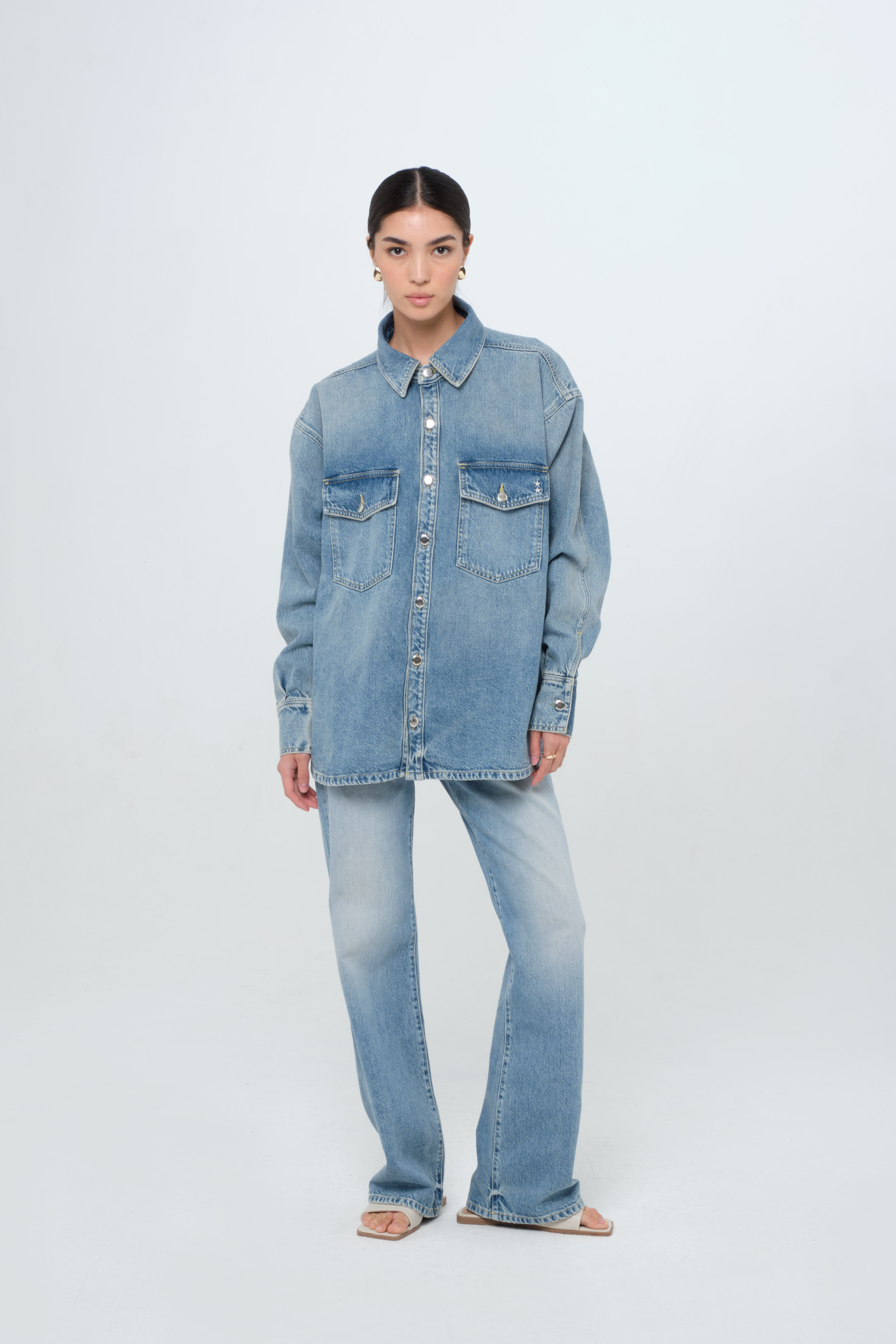 Noa women’s oversize shirt in smoke blue wash, 100% rigid cotton denim, worn by a model with jeans.