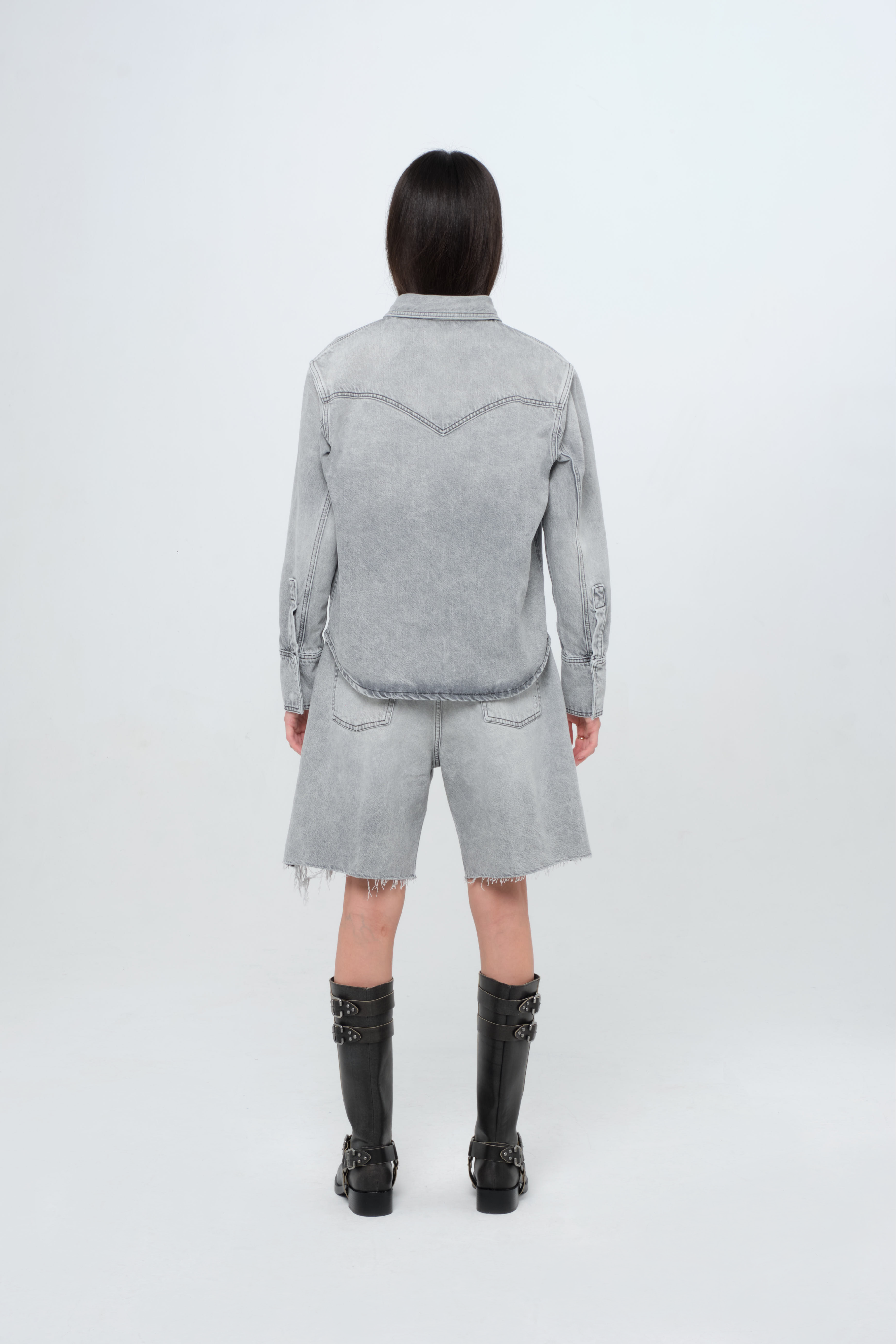 Back view of Norah women’s regular shirt in gray wash, 100% rigid cotton denim, worn by a model with shorts.

