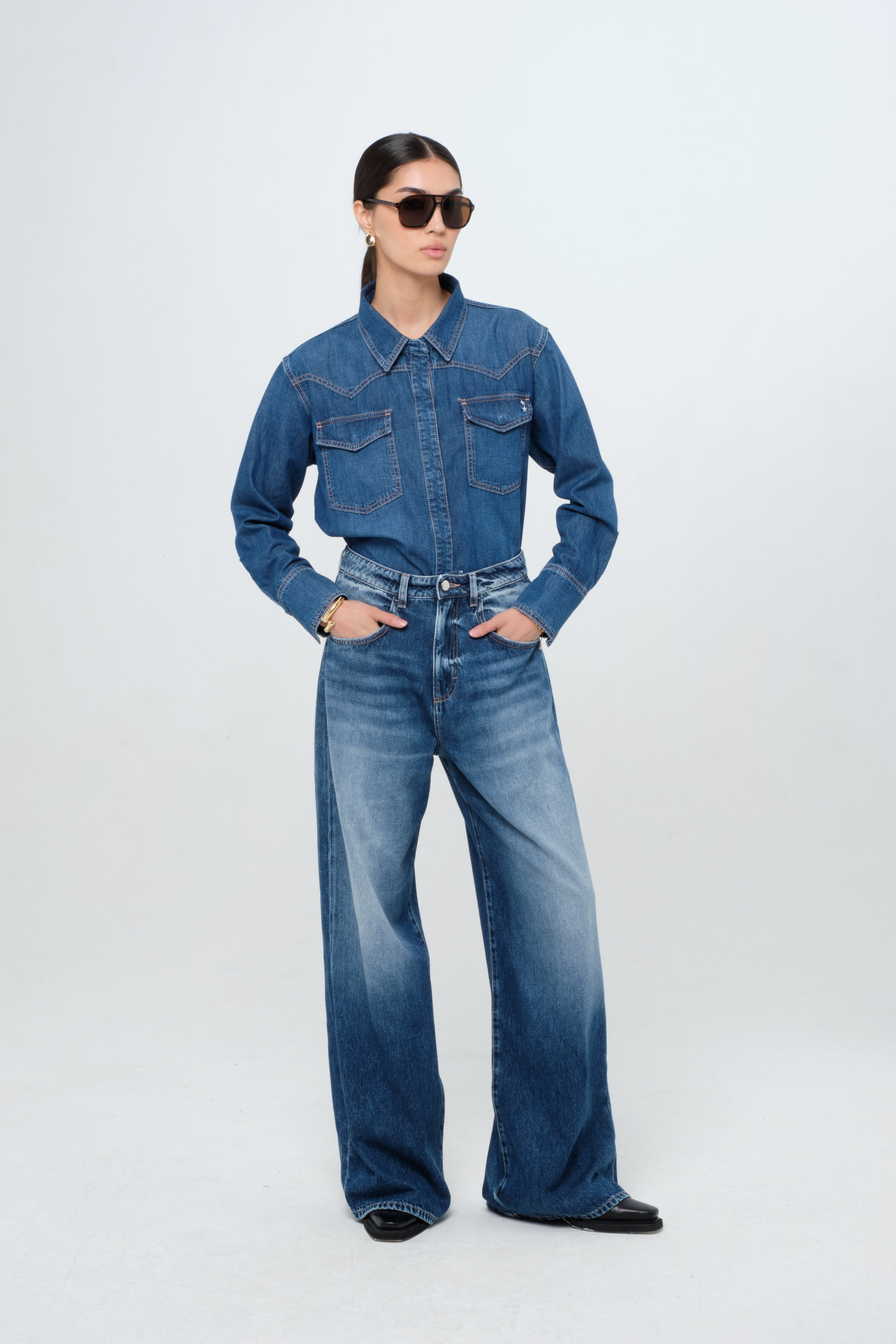 Norah women’s shirt in dark wash, 100% rigid soft cotton denim, worn by a model with jeans.

