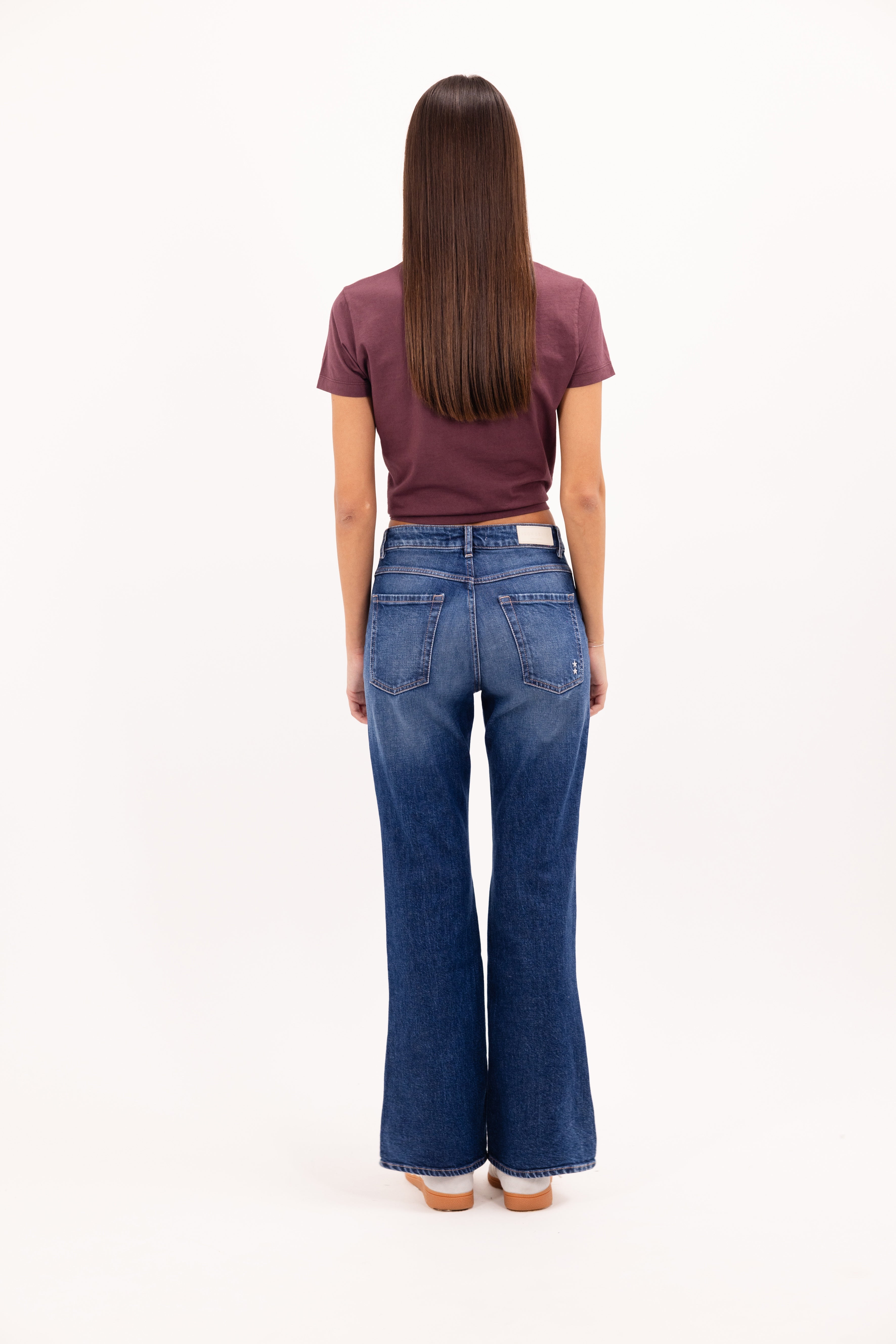 Back view of Pammy women’s slim flared jeans in eclipse wash, 99% cotton denim and 1% Elastan fibers, worn by a model with a cherry t-shirt.