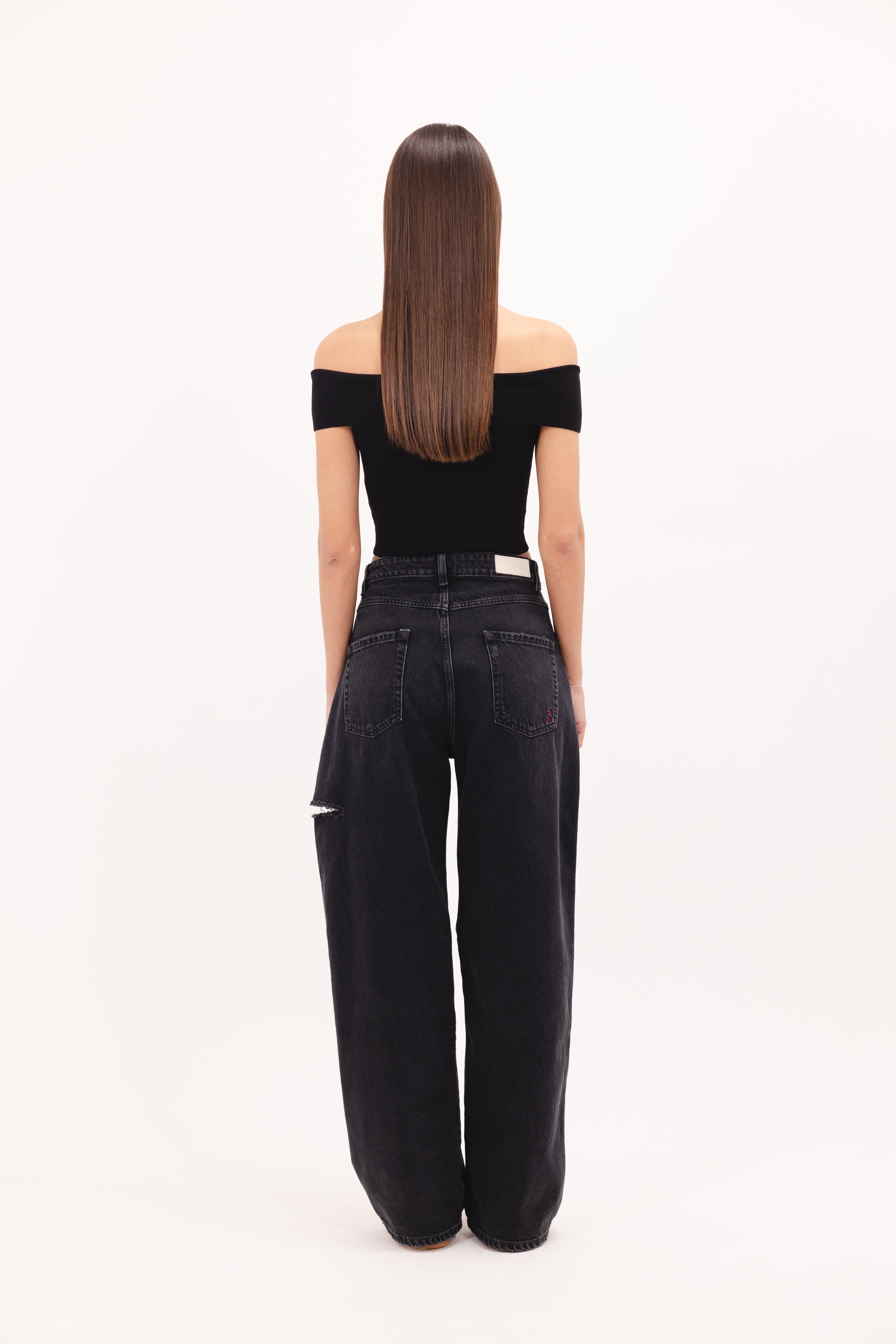 Back view of Poppy women’s wide leg jeans in graphite black wash, 100% rigid cotton denim, worn by a model with a black top.