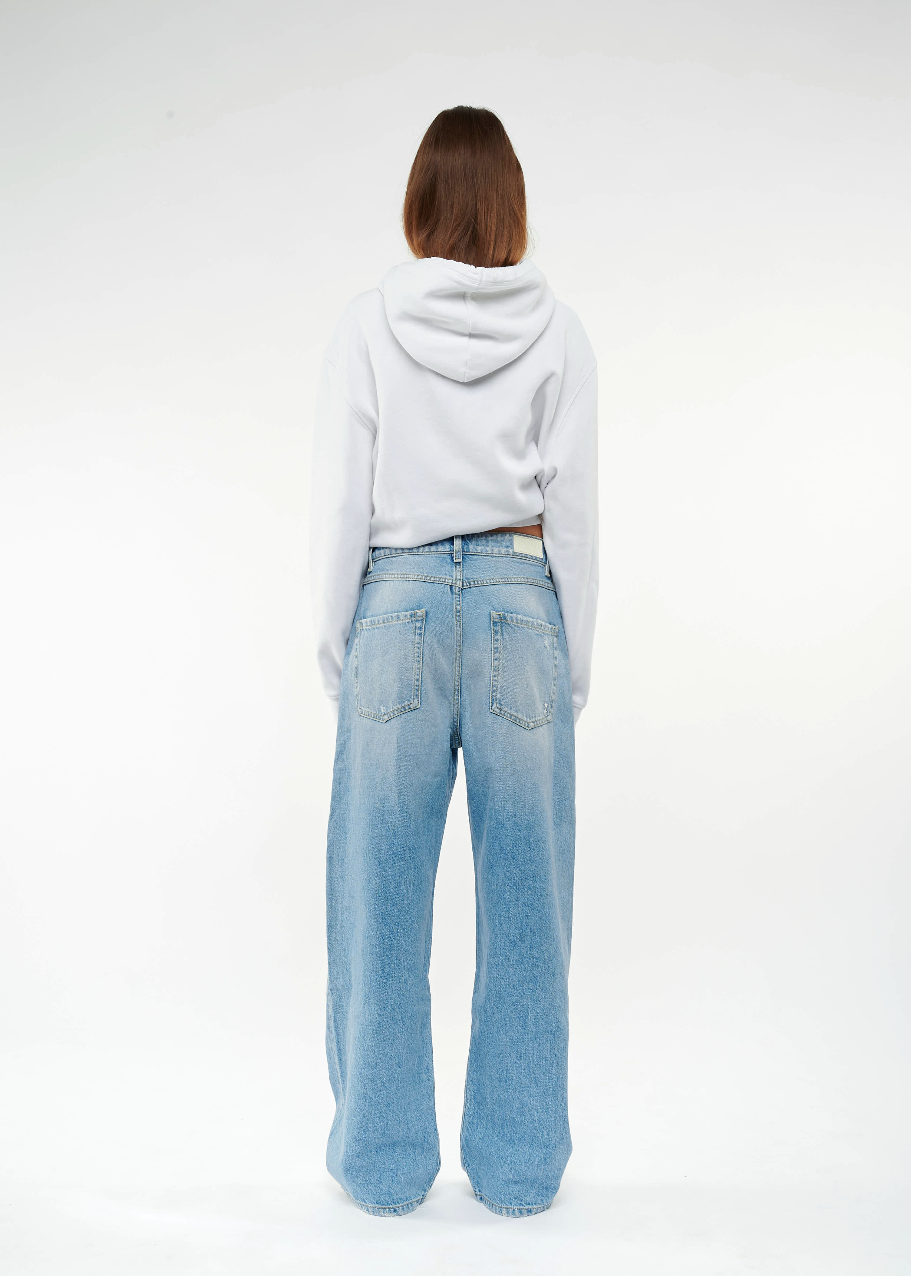 Back view of Poppy women’s wide leg jeans in medium wash, 100% rigid cotton denim, worn by a model with a white sweatshirt.