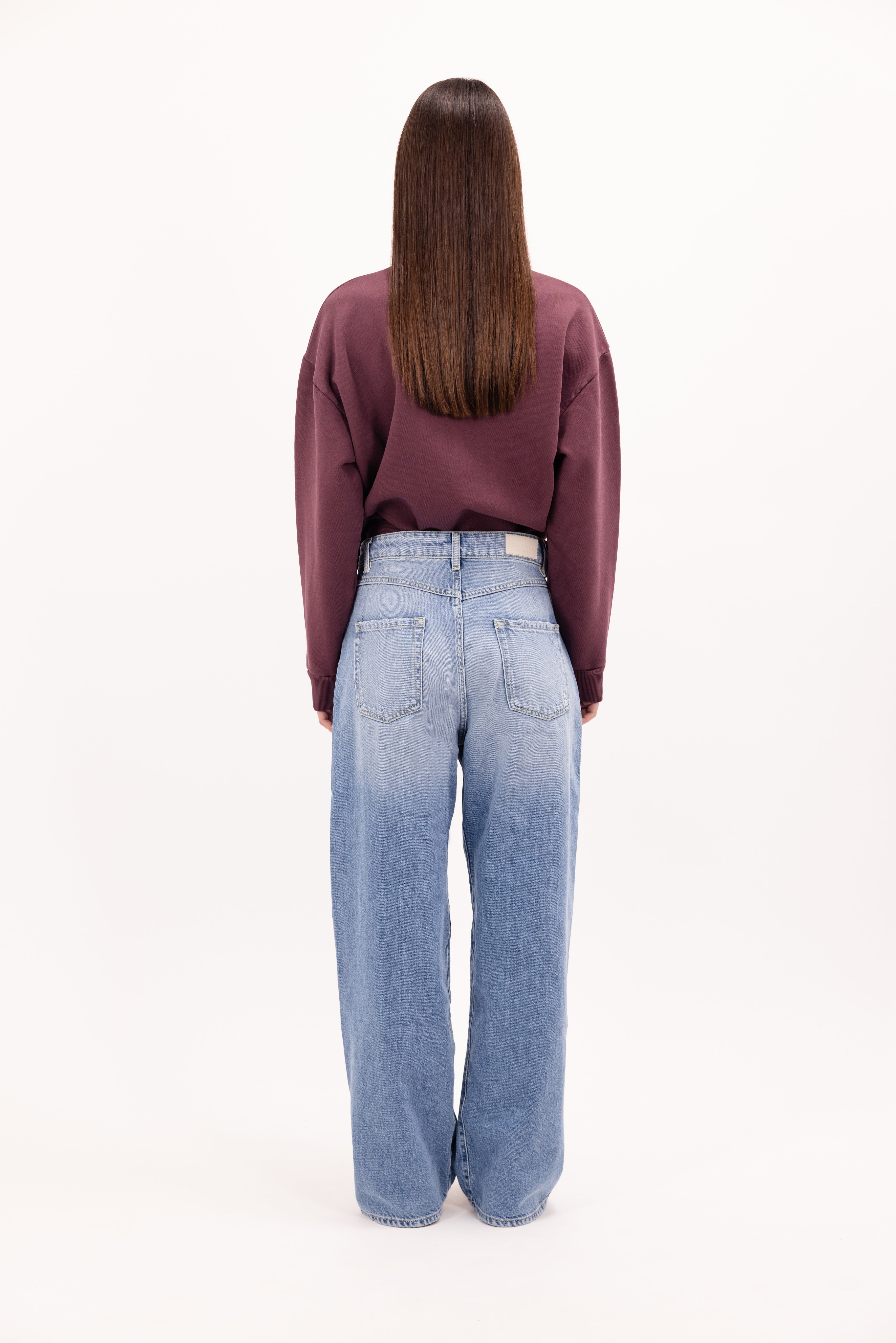 Back view of Poppy women’s wide leg jeans in sky blue wash, 100% rigid cotton denim, worn by a model with a cherry sweatshirt.