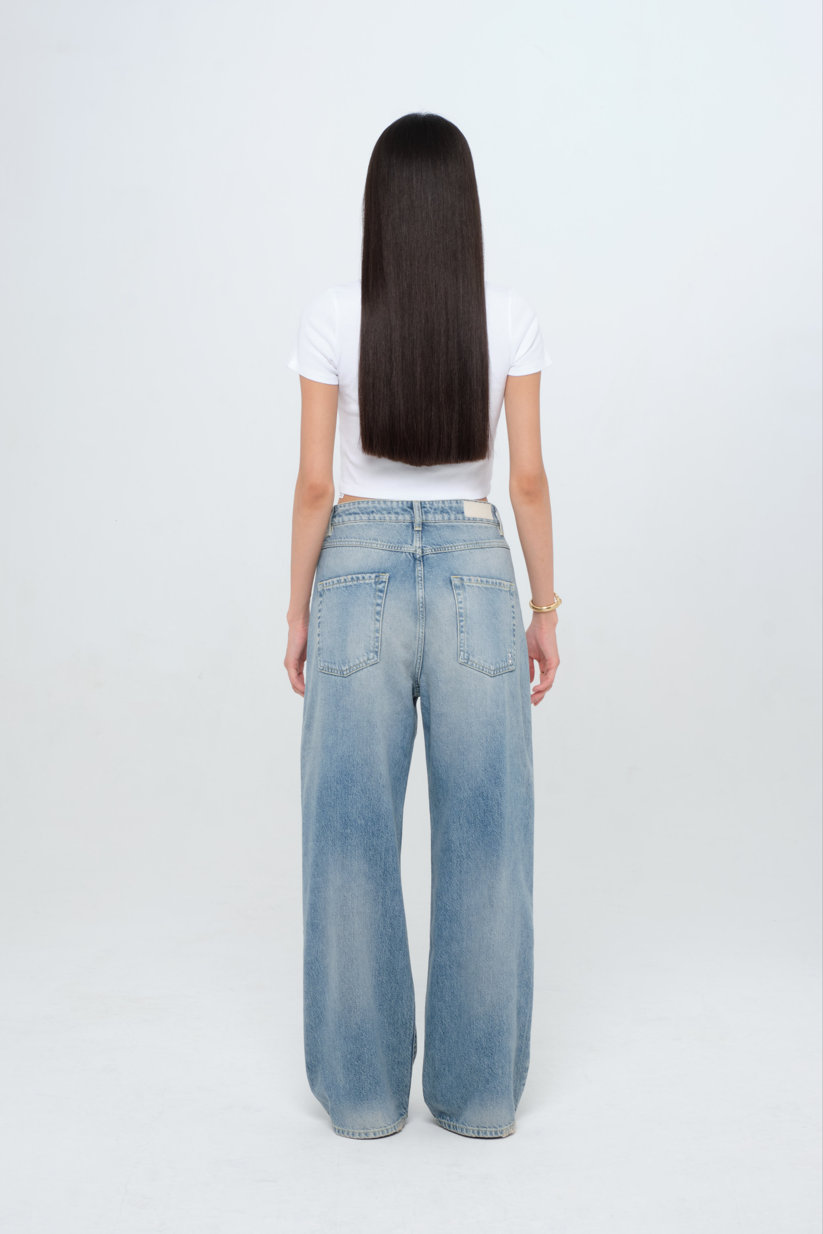 Back view of Poppy women’s wide leg jeans in smoke blue wash, 100% rigid cotton denim, worn by a model with a white t-shirt.