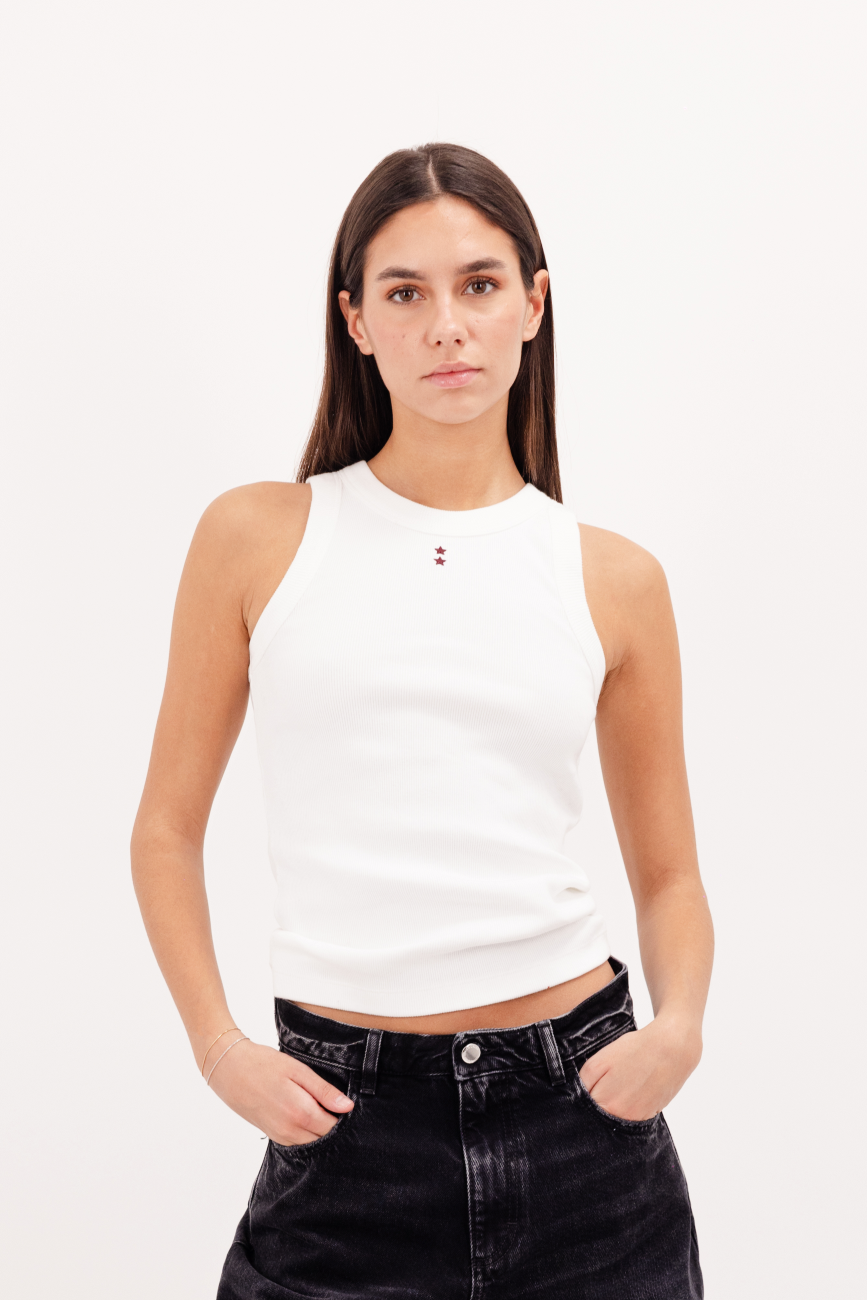 Raya women’s tank top in white, 50% Md - 49% Co - 1% Ea, worn by a model with jeans.
