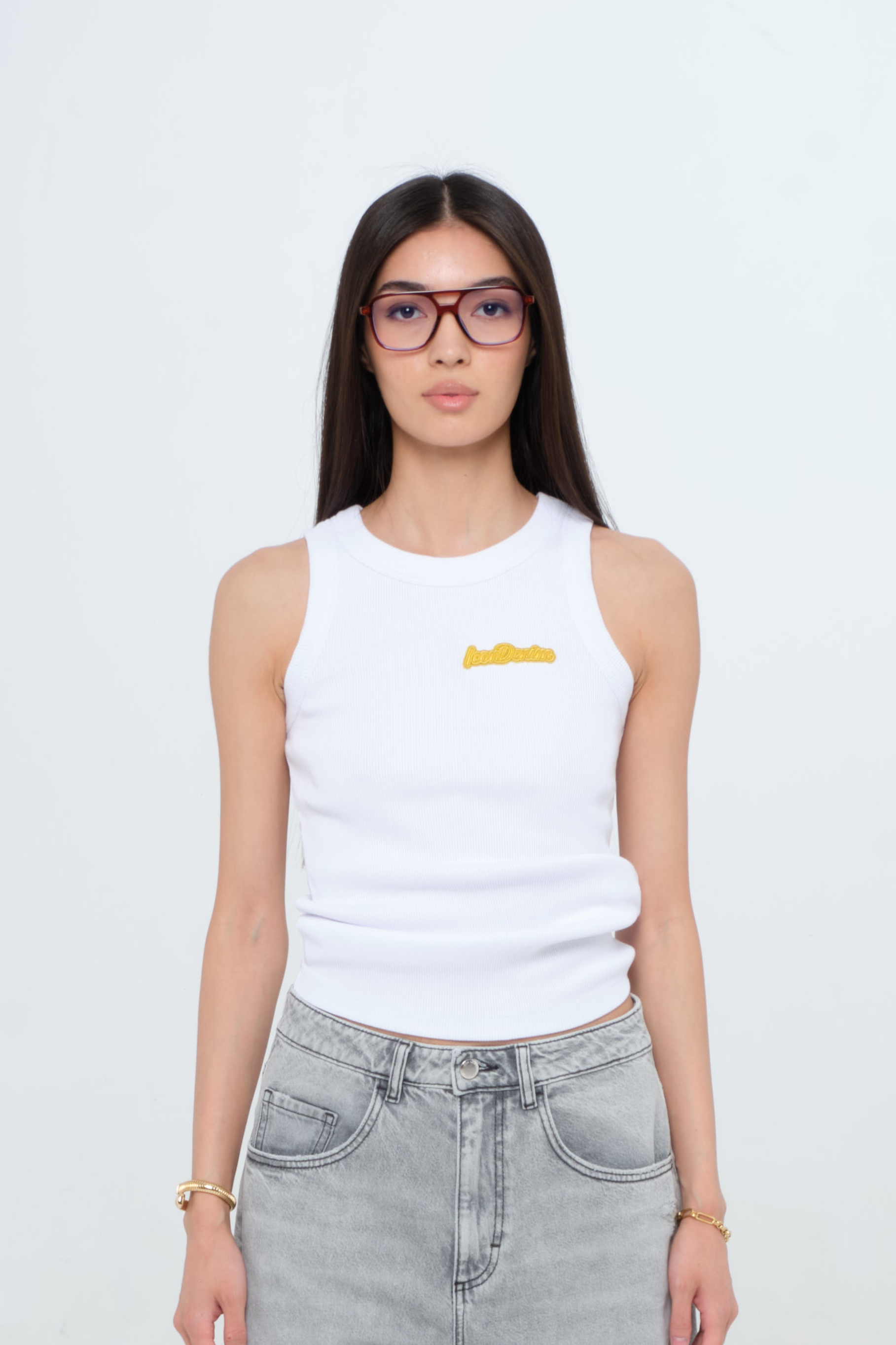 Raya women’s tank top in white, 50% Md - 49% Co - 1% Ea, worn by a model with jeans.