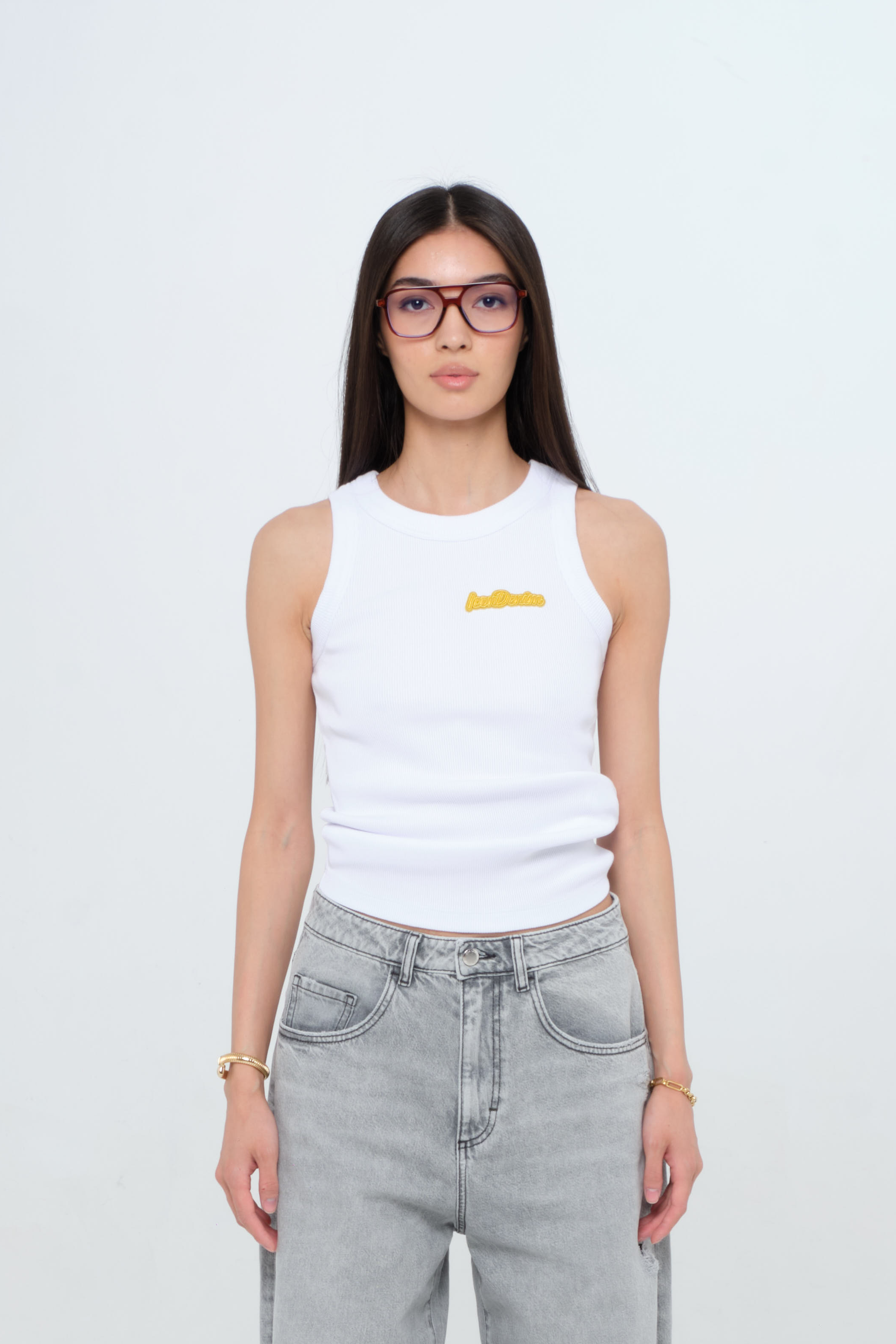 Raya women’s tank top in white, 50% Md - 49% Co - 1% Ea, worn by a model with jeans.