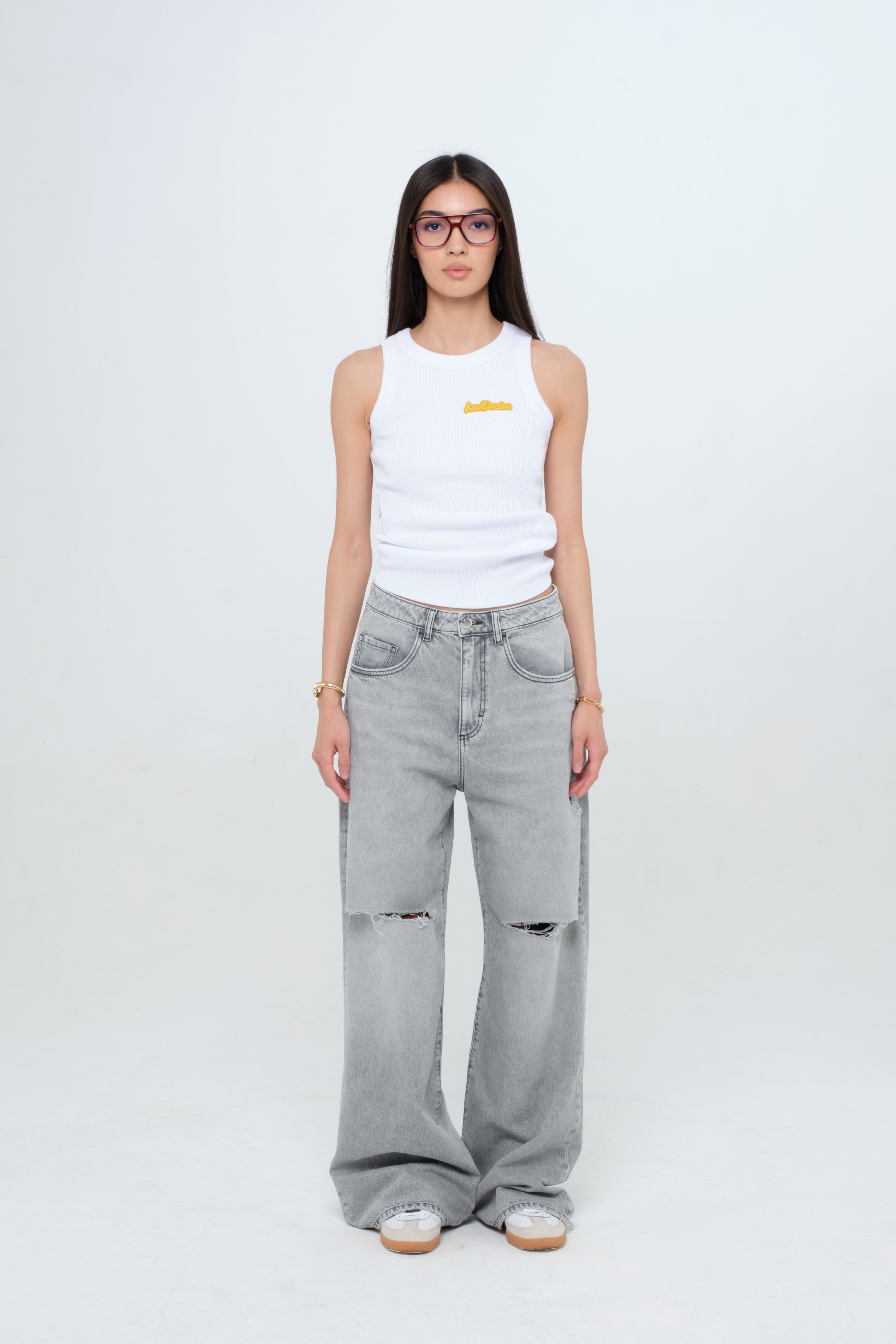 Raya women’s tank top in white, 50% Md - 49% Co - 1% Ea, worn by a model with jeans.