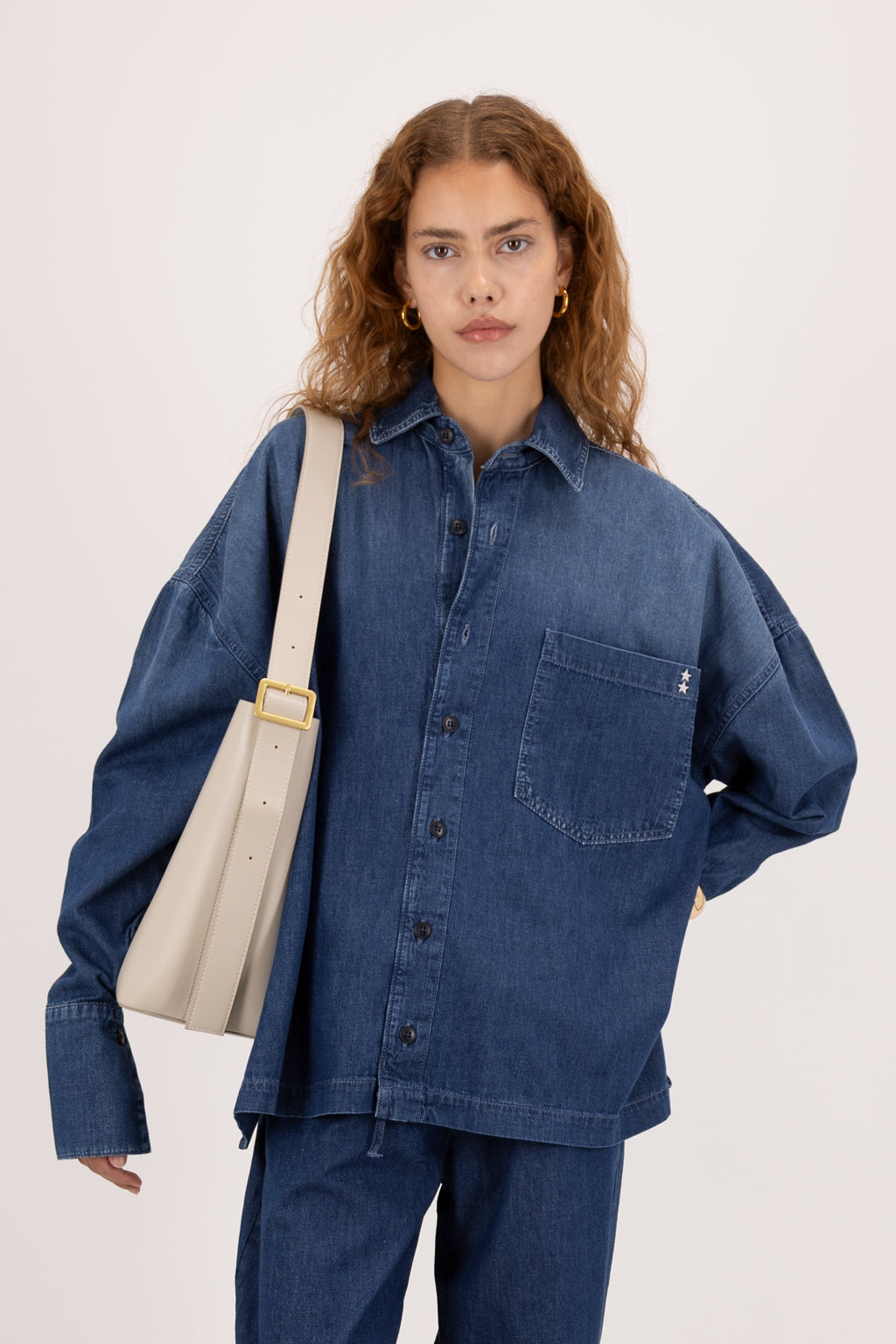 Rena women’s oversize shirt in night wash, 100% ultra light cotton denim, worn by a model with jeans.
