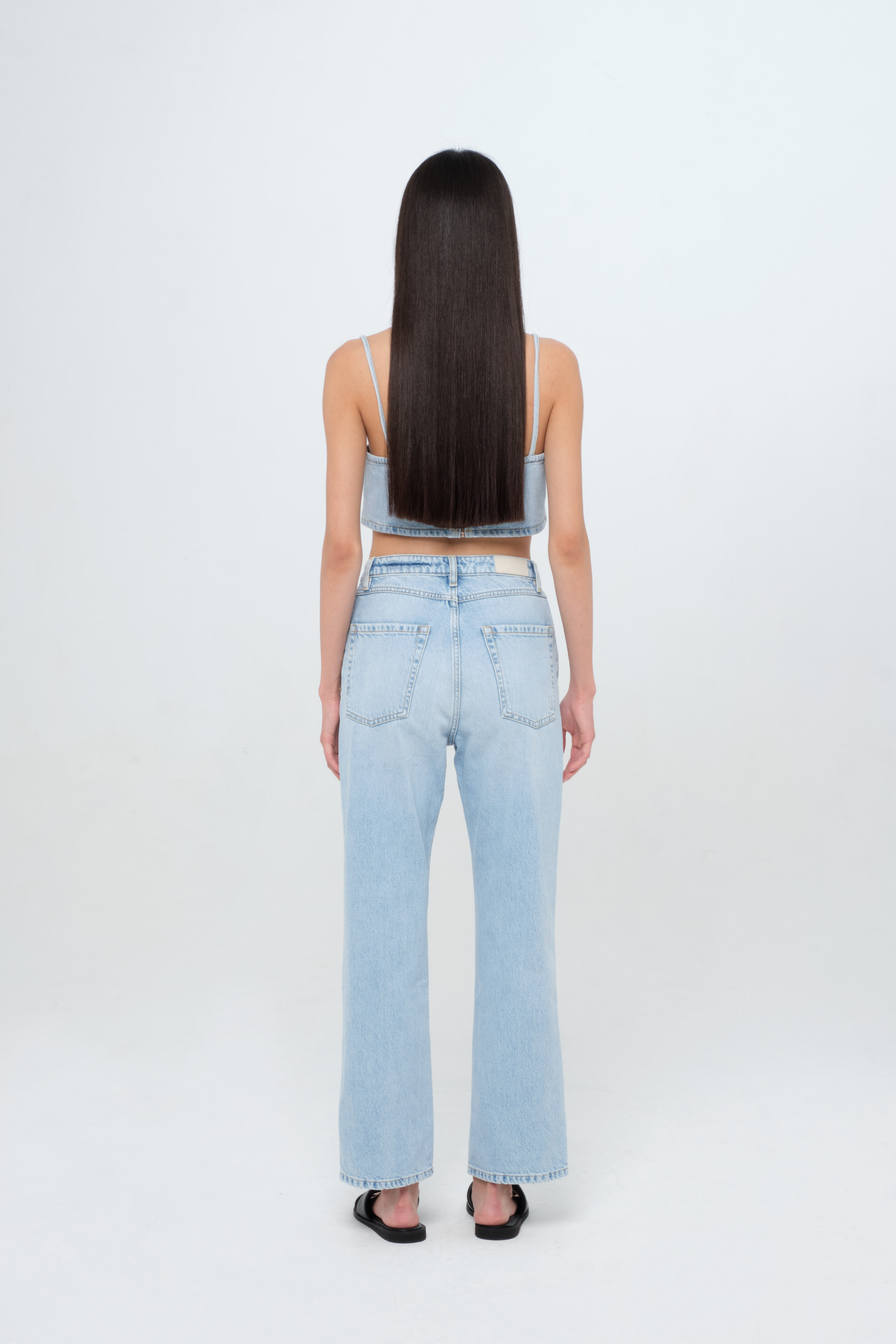 Back view of Rose women’s straight leg jeans in light wash, 100% rigid cotton denim, worn by a model with a denim top.