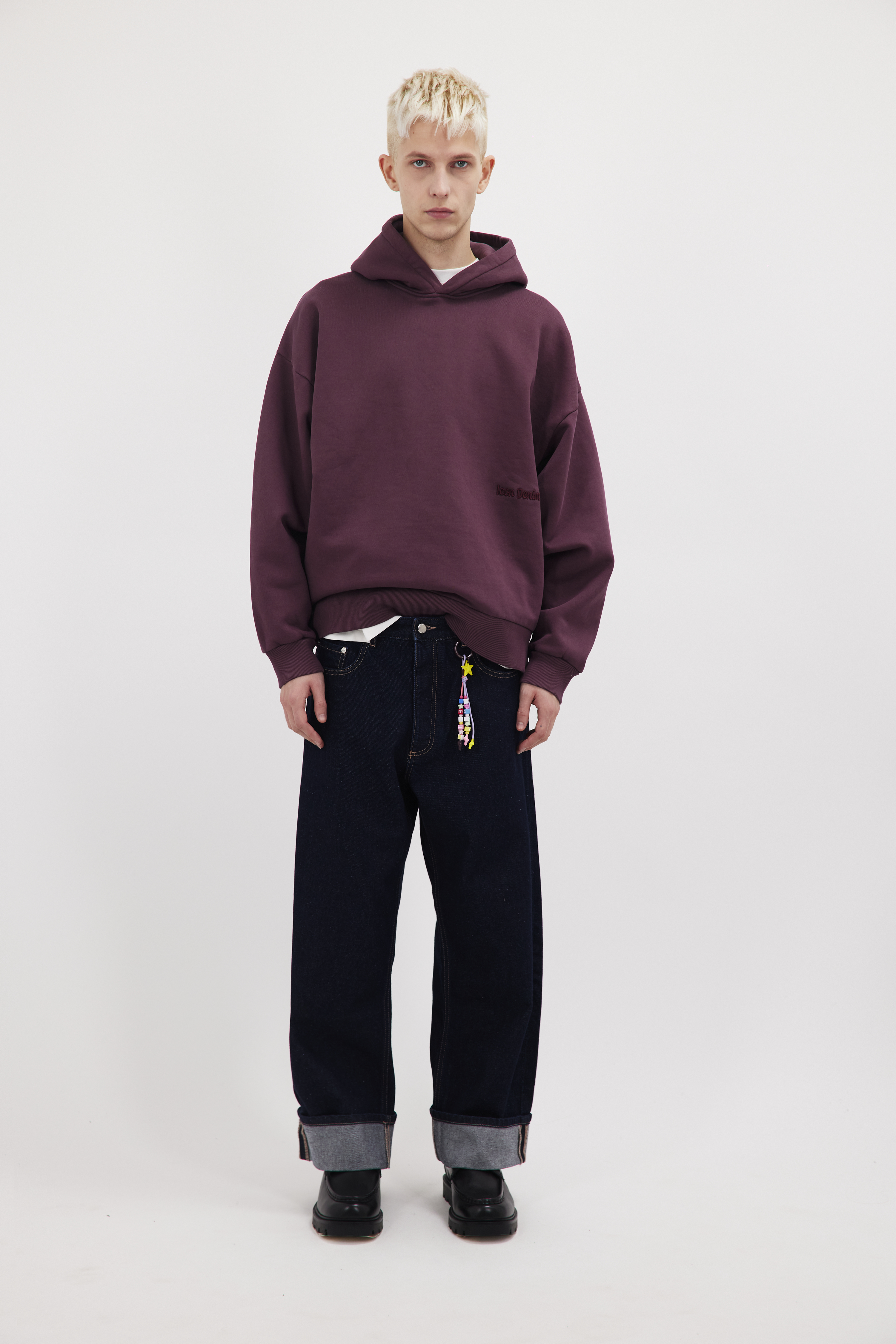 Will men’s wide leg baggy jeans in indigo raw wash, 100% rigid cotton denim, worn by a model with a cherry sweatshirt.