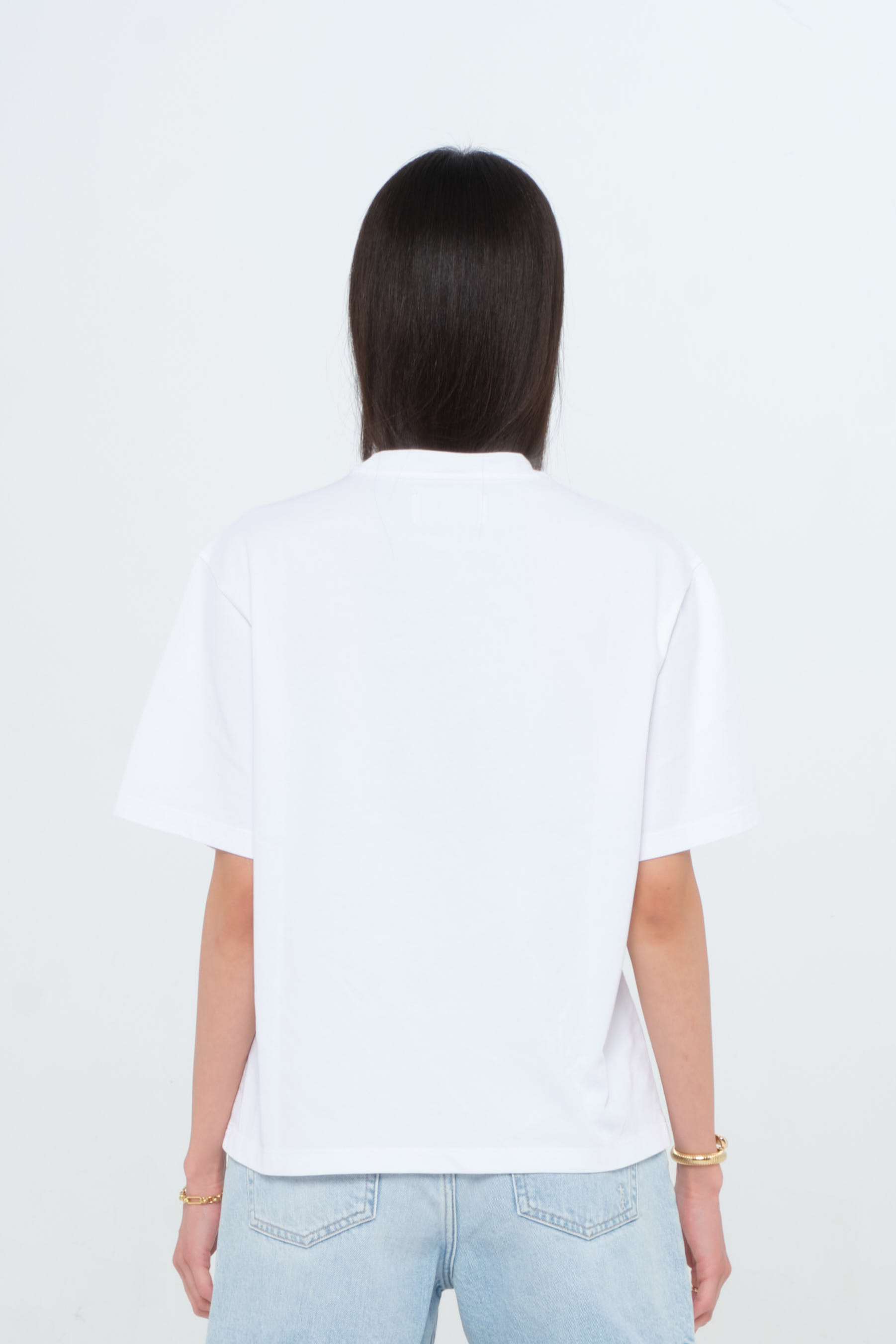 Back view of Sammy women’s t-shirt in white, 100% cotton, worn by a model with shorts.
