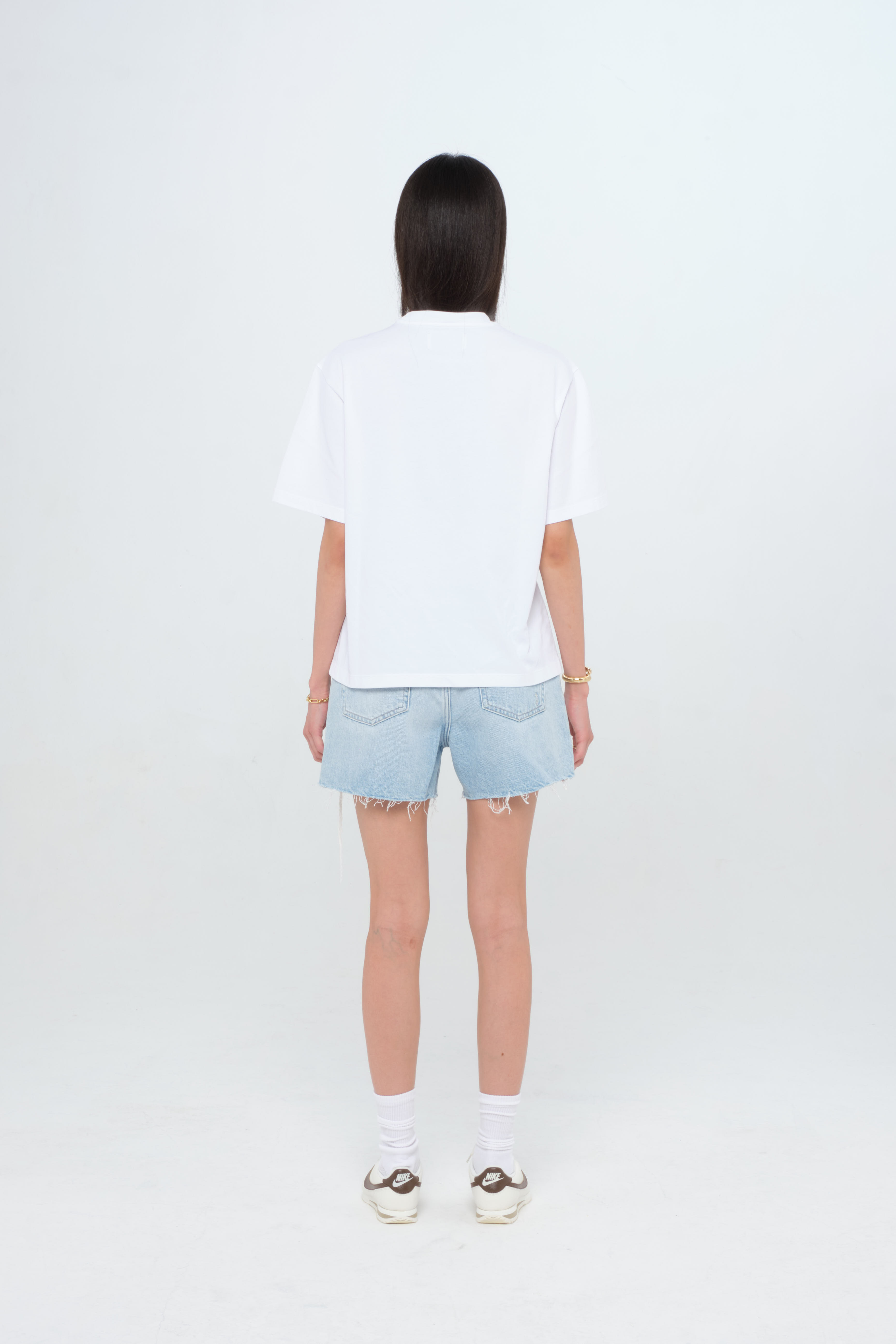 Back view of Sammy women’s t-shirt in white, 100% cotton, worn by a model with shorts.
