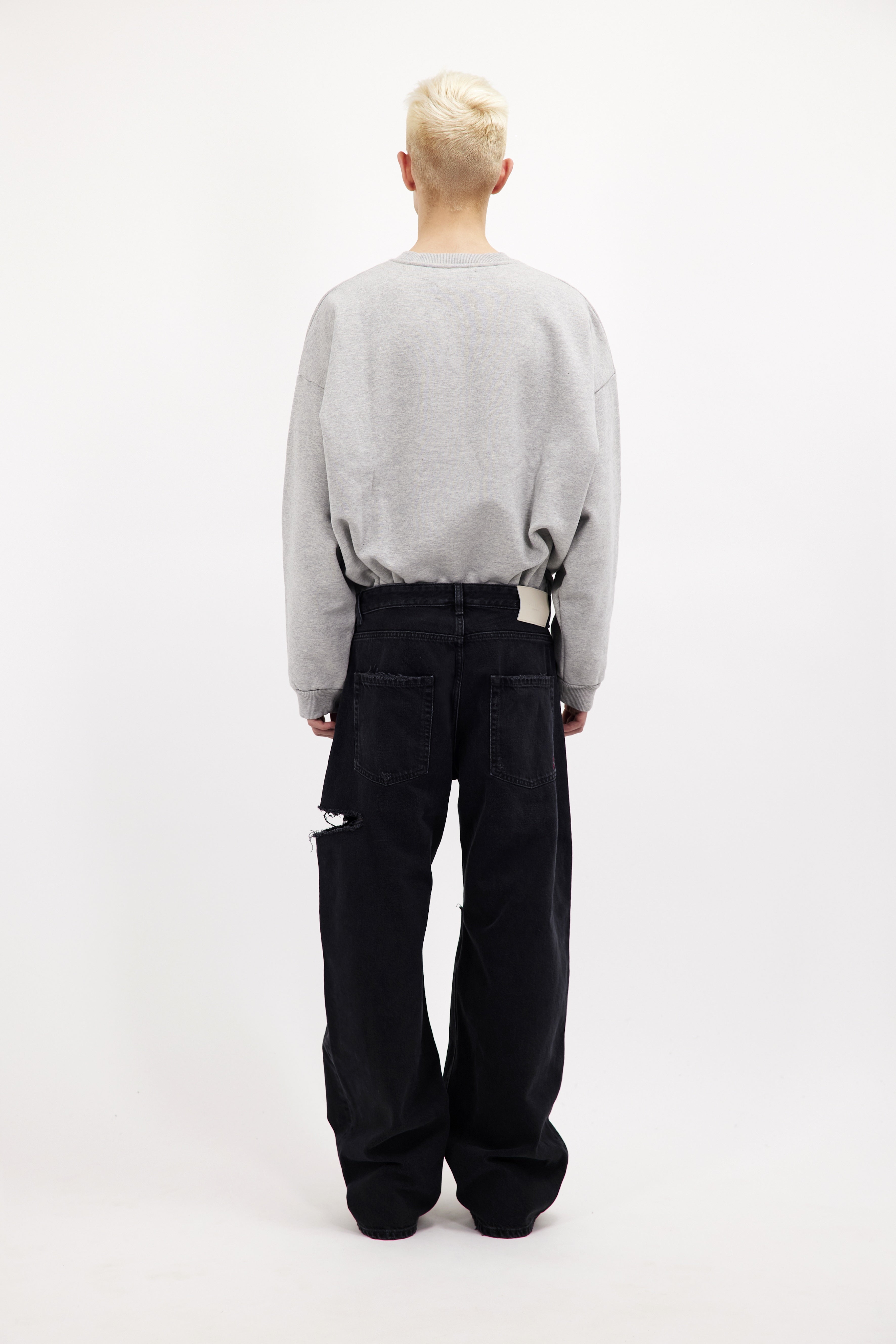 Back view of Scott men’s wide leg jeans in graphite black wash, 100% rigid cotton denim, worn by a model with a grey sweatshirt.