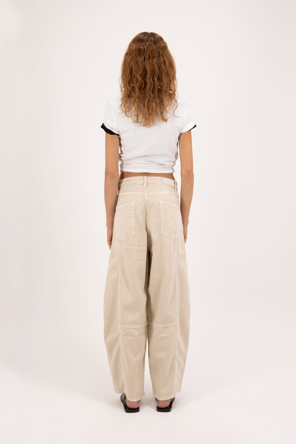 Back view of Sia women’s balloon jeans in desert wash, 100% rigid soft cotton denim, worn by a model with a white t-shirt.