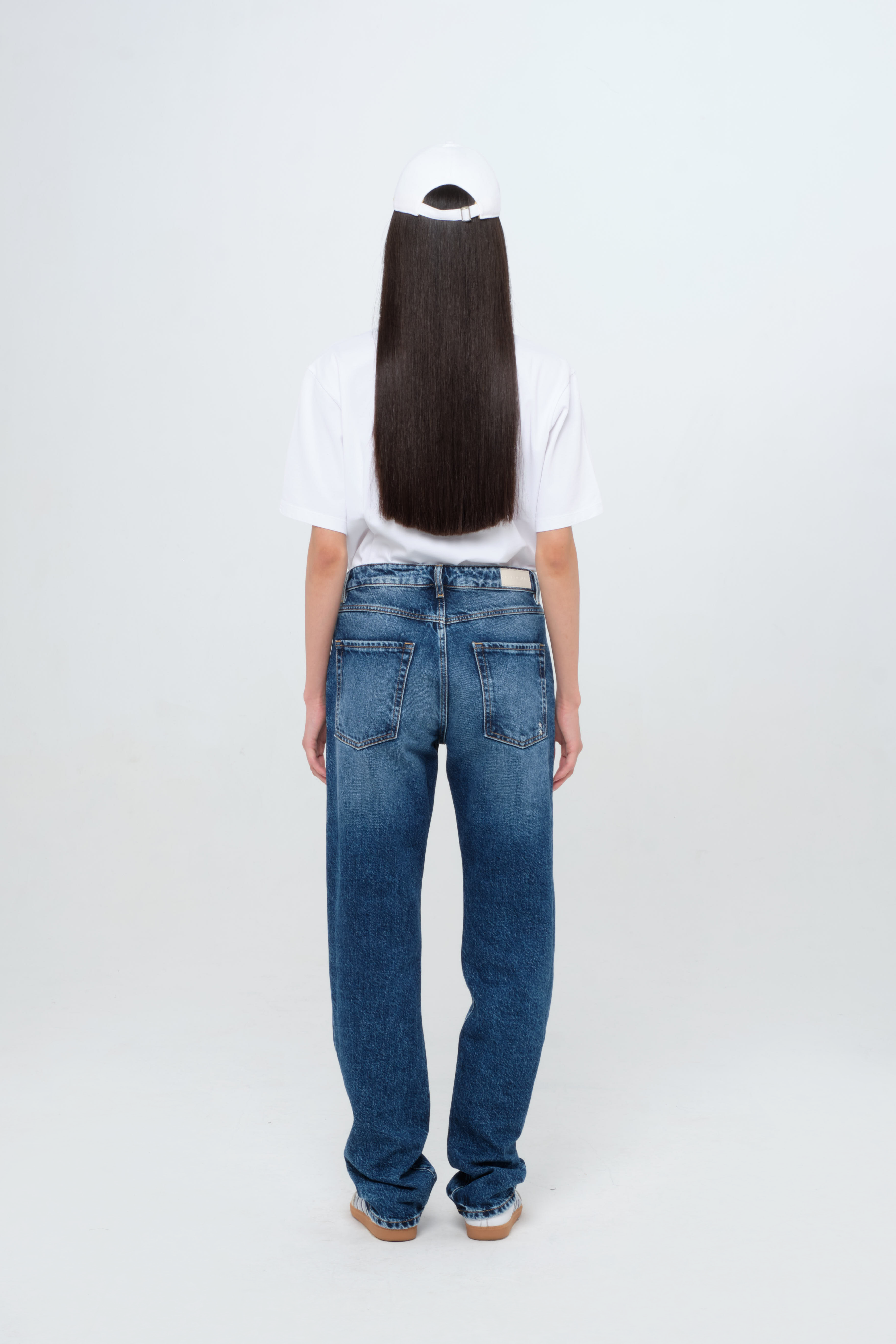 Back view of Skye women’s regular jeans in dark wash, 100% rigid cotton denim, worn by a model with a white t-shirt.
