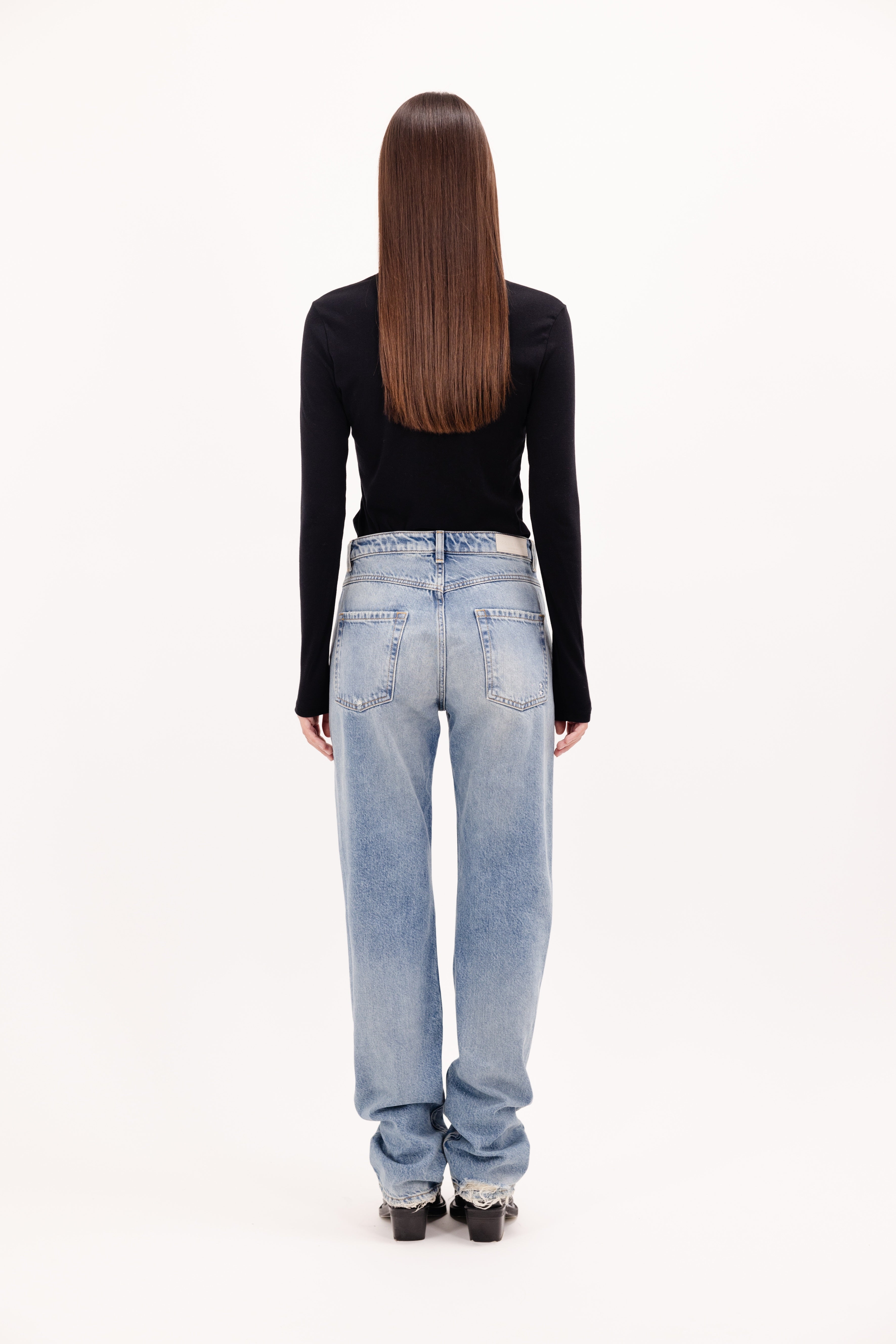 Back view of Skye women’s regular jeans in smoke blue wash, 100% rigid cotton denim, worn by a model with a black longsleeve.
