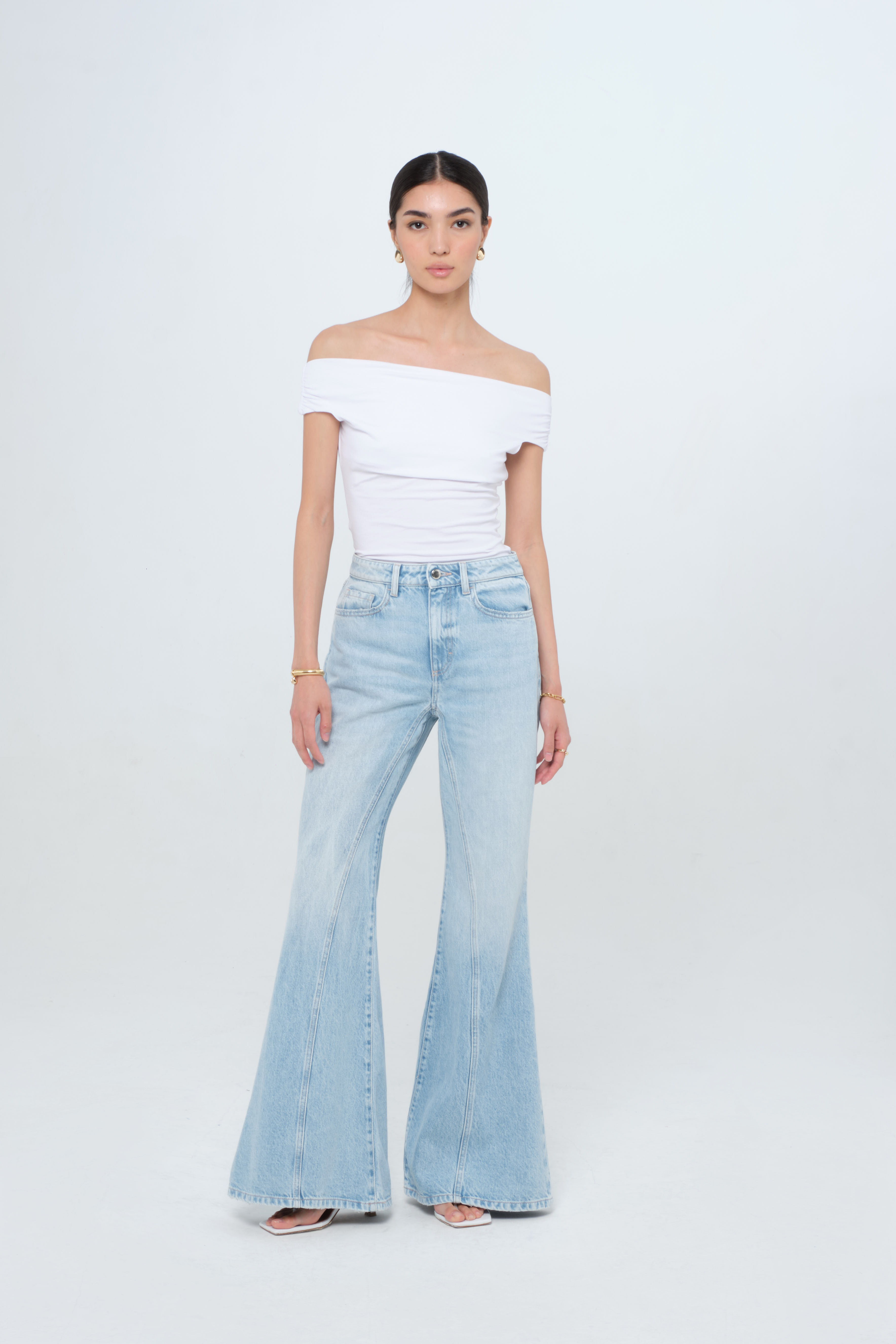 Stella women’s flared leg jeans in light wash, 100% rigid cotton denim, worn by a model with a white top.
