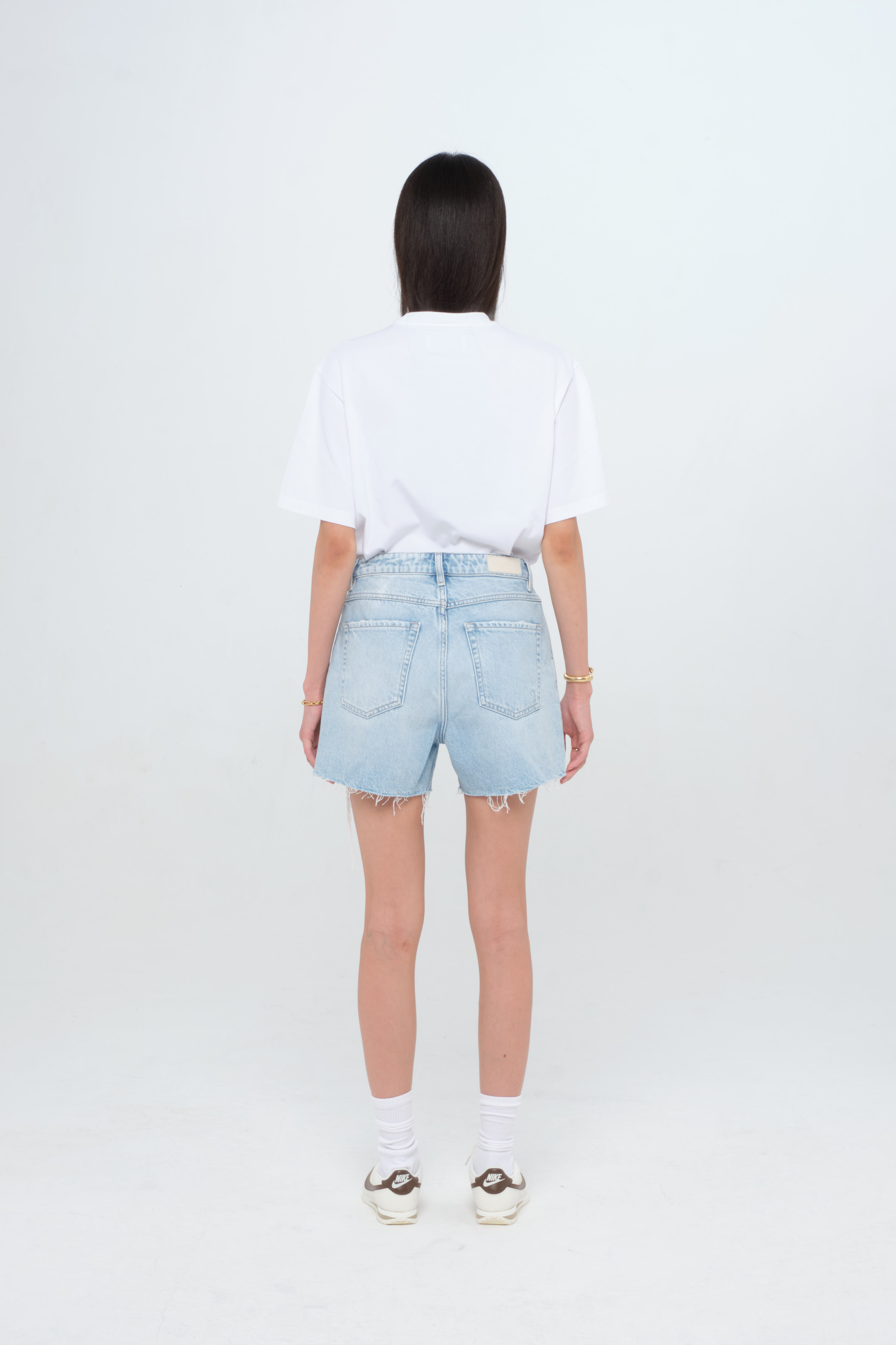 Back view of Tam X women’s straight leg short jeans in light wash, 100% rigid cotton denim, worn by a model with a white t-shirt.
