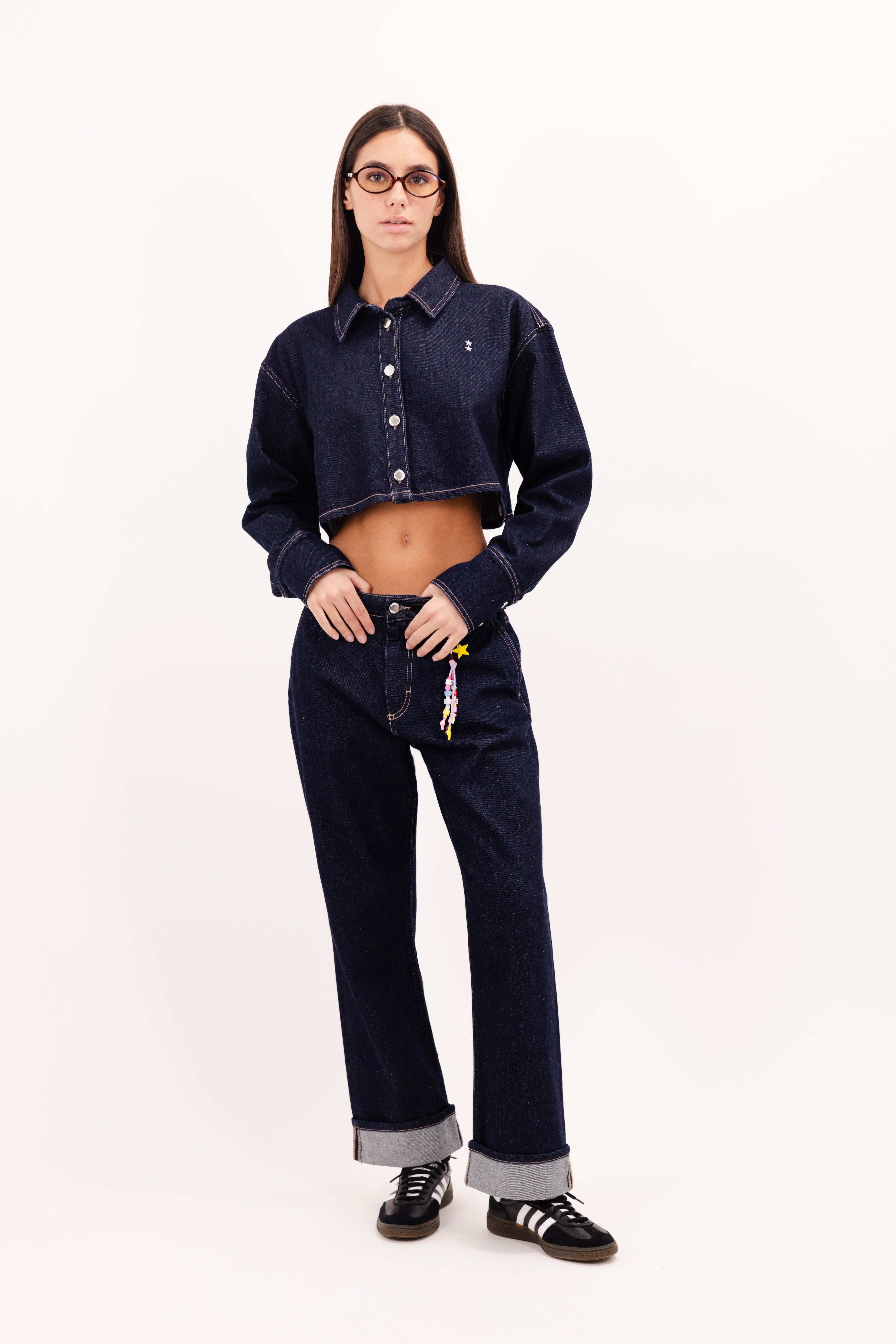 Tiny women’s flared leg jeans in indigo raw, 100% rigid cotton denim, worn by a model with a denim crop shirt.