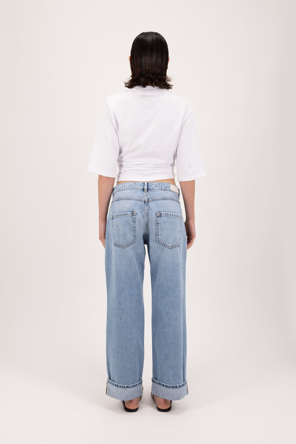 Back view of Tiny women’s wide leg cropped jeans in sky blue wash, 100% rigid soft cotton denim, worn by a model with a white t-shirt.