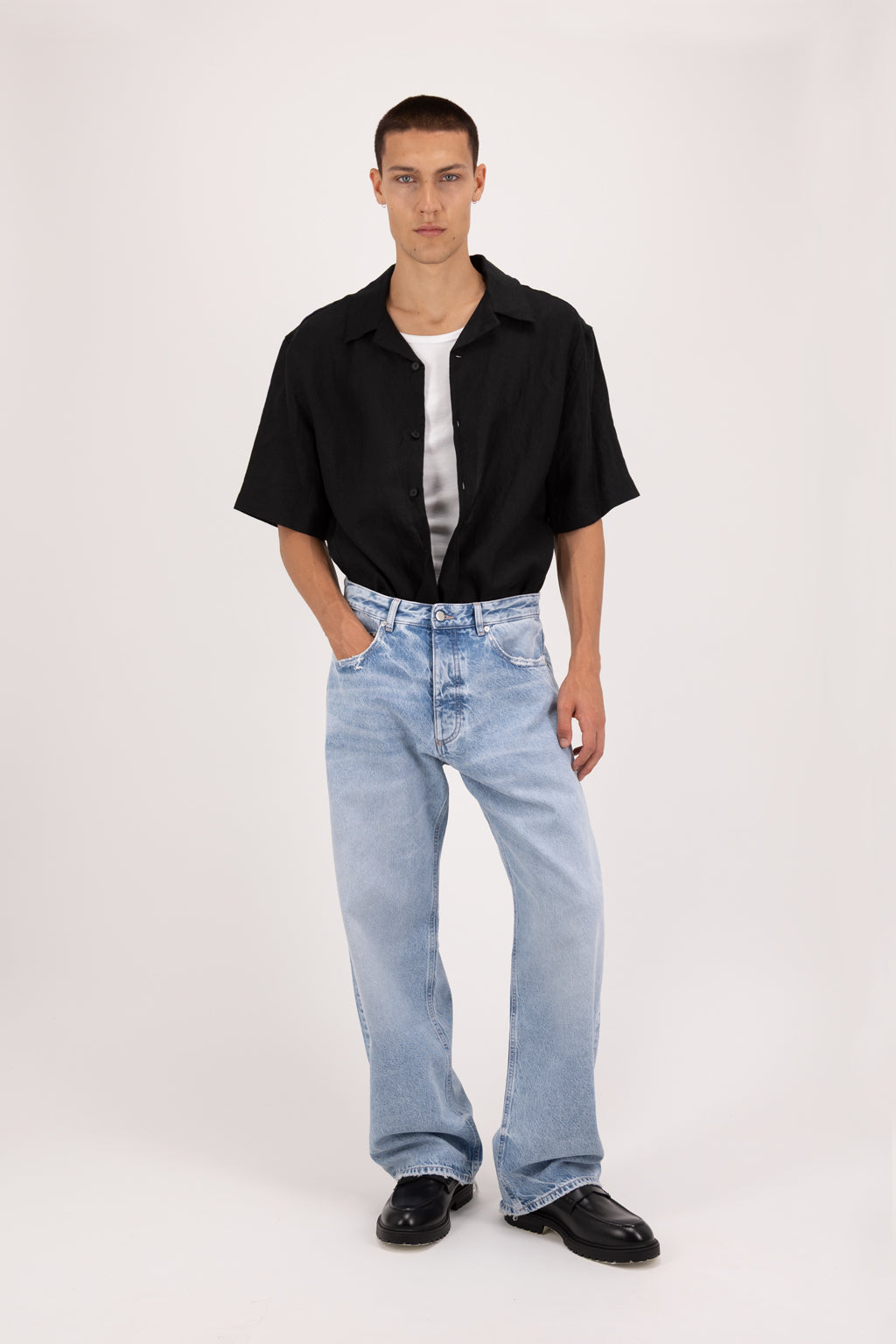 Will Eco men’s wide leg jeans in arid blue wash, 100% organic rigid cotton denim, worn by a model with a black shirt.