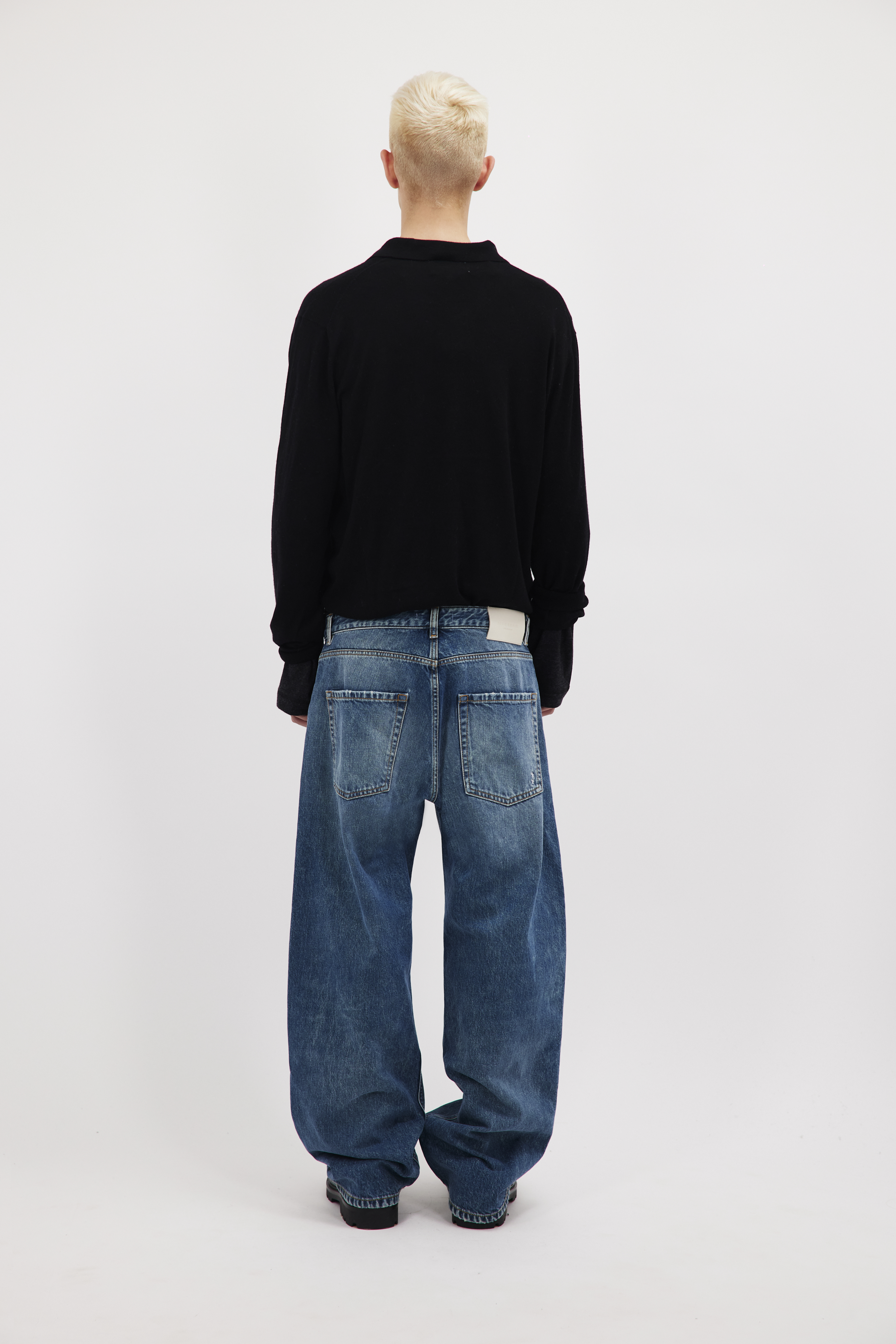 Back view of Will men’s wide leg jeans in aged stone wash, 100% rigid cotton denim, worn by a model with a black longsleeve.