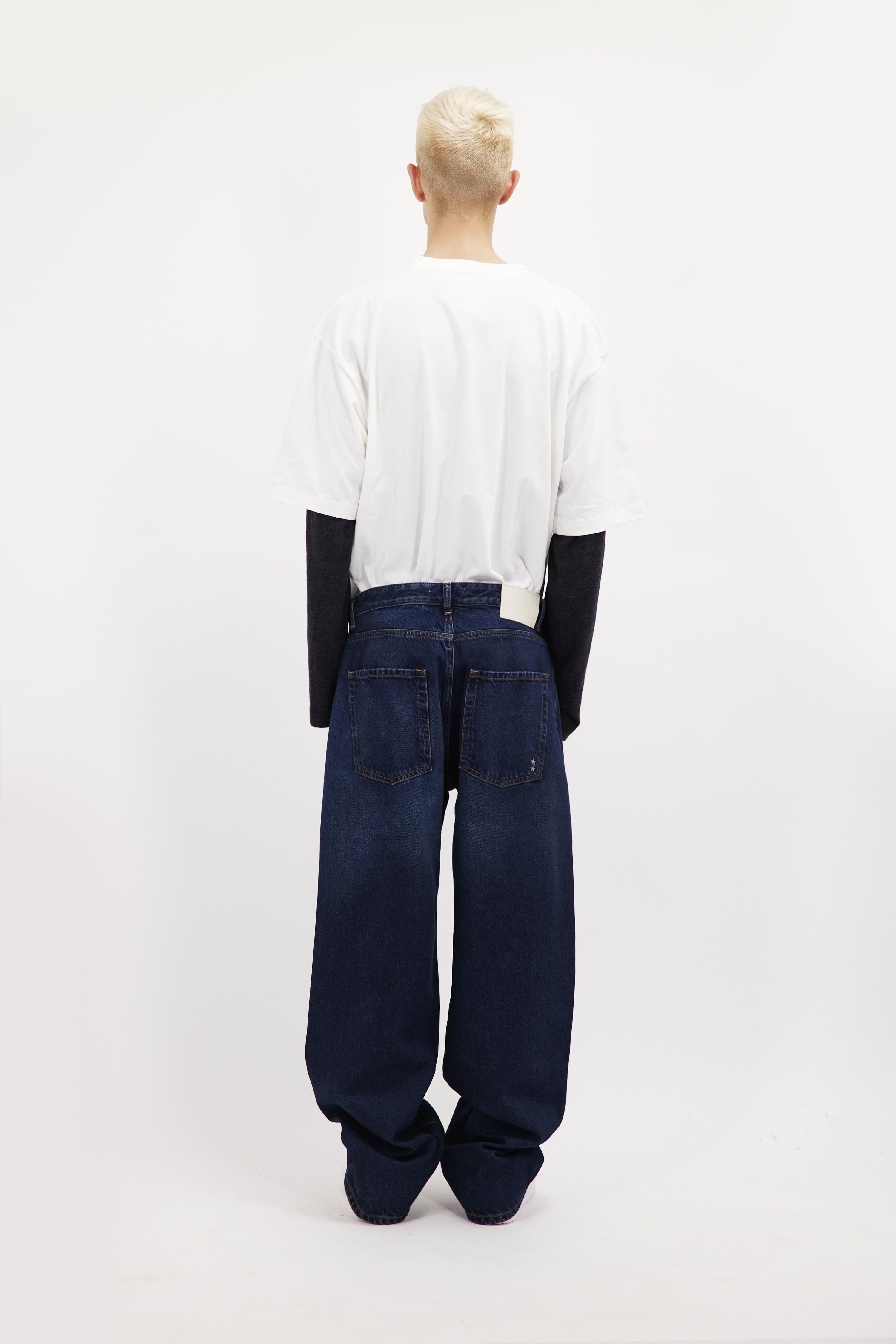 Back view of Will men’s wide leg jeans in dusty blue wash, 100% rigid cotton denim, worn by a model with a white t-shirt.