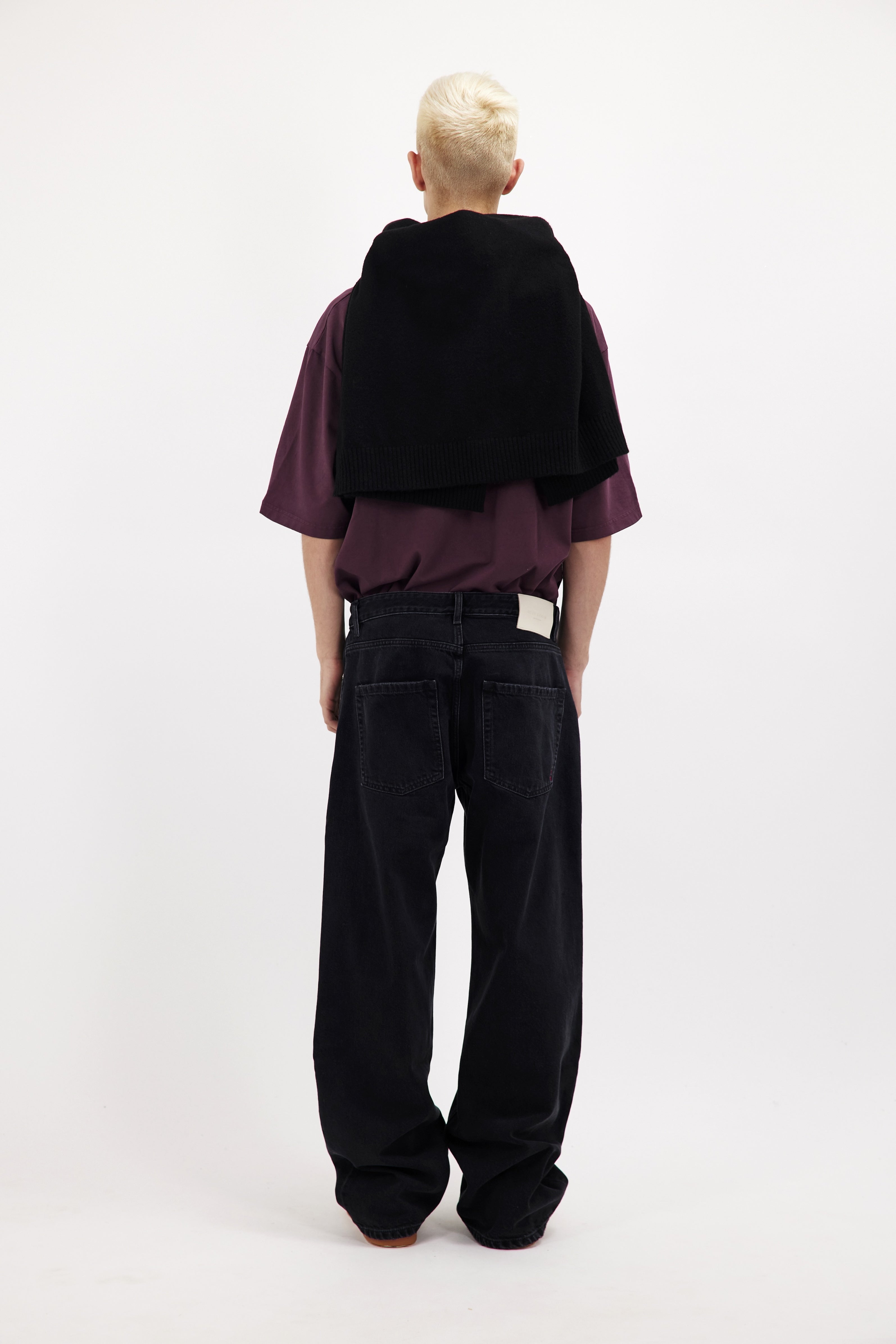 Back view of Will men’s wide leg jeans in graphite black wash, 100% rigid cotton denim, worn by a model with a cherry t-shirt.