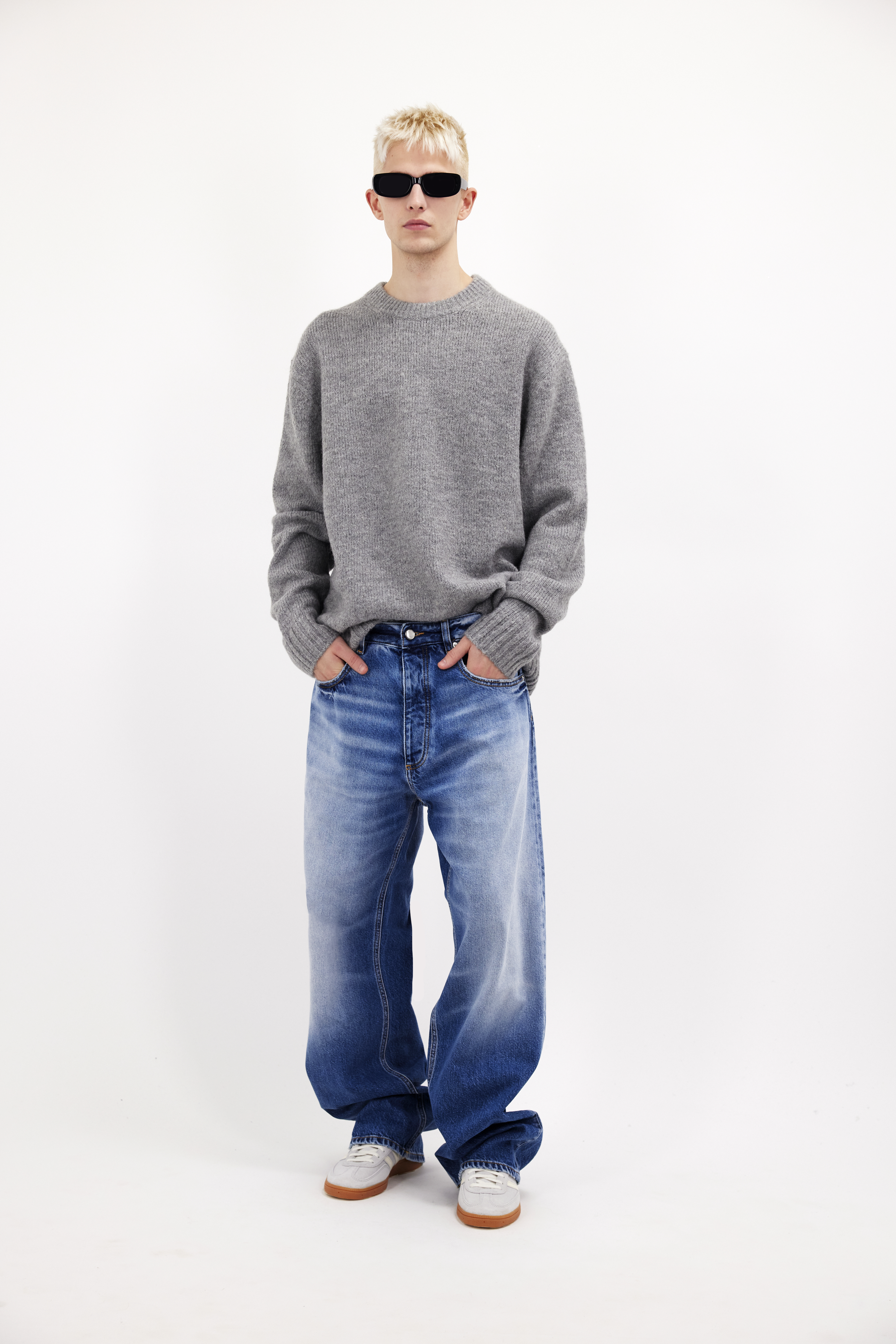 Will men’s wide leg jeans in misty blue wash, 100% rigid cotton denim, worn by a model with a grey knit.