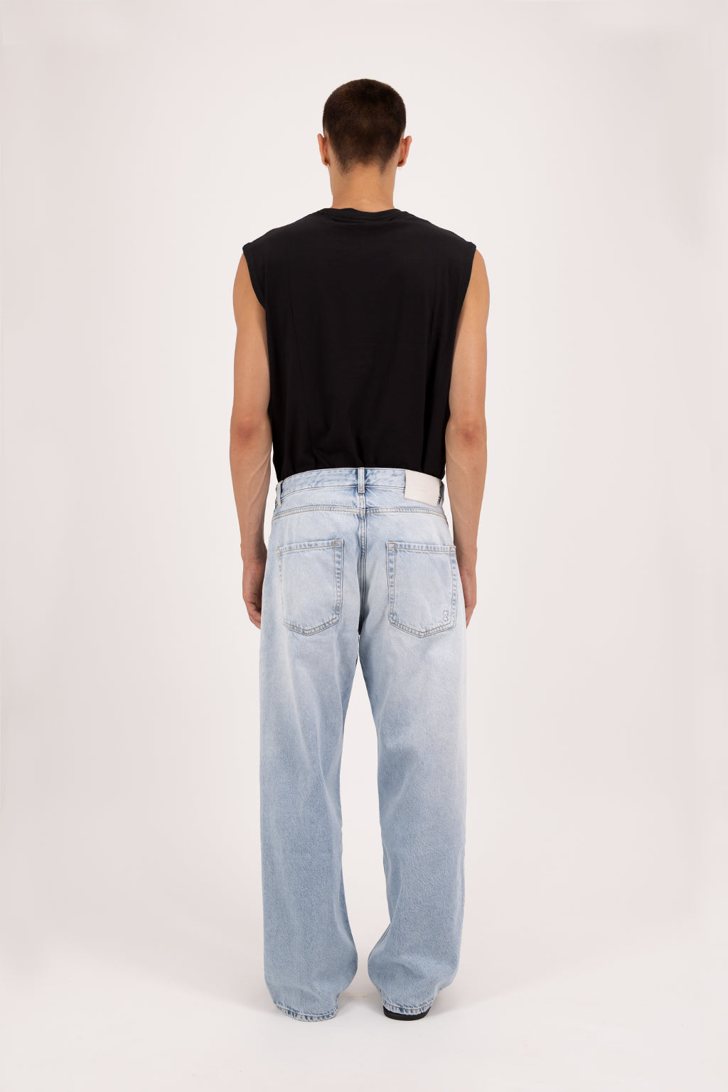 Back view of Will men’s wide leg jeans in sky blue wash, 100% rigid cotton denim, worn by a model with a black top.