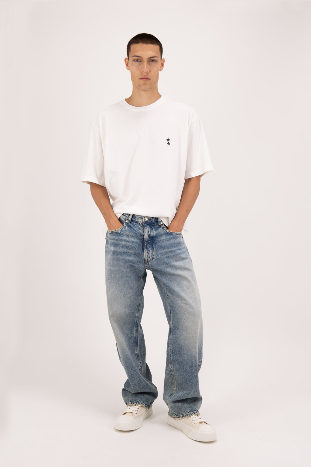 Will men’s wide leg jeans in smoke blue wash, 100% rigid cotton denim, worn by a model with a white t-shirt.